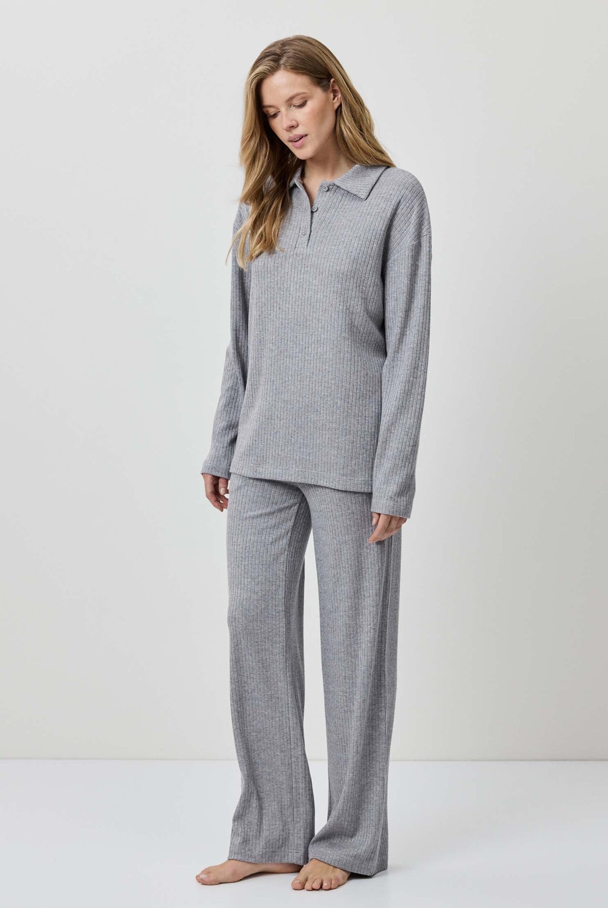 Woman wearing a gray pajama set against a white background