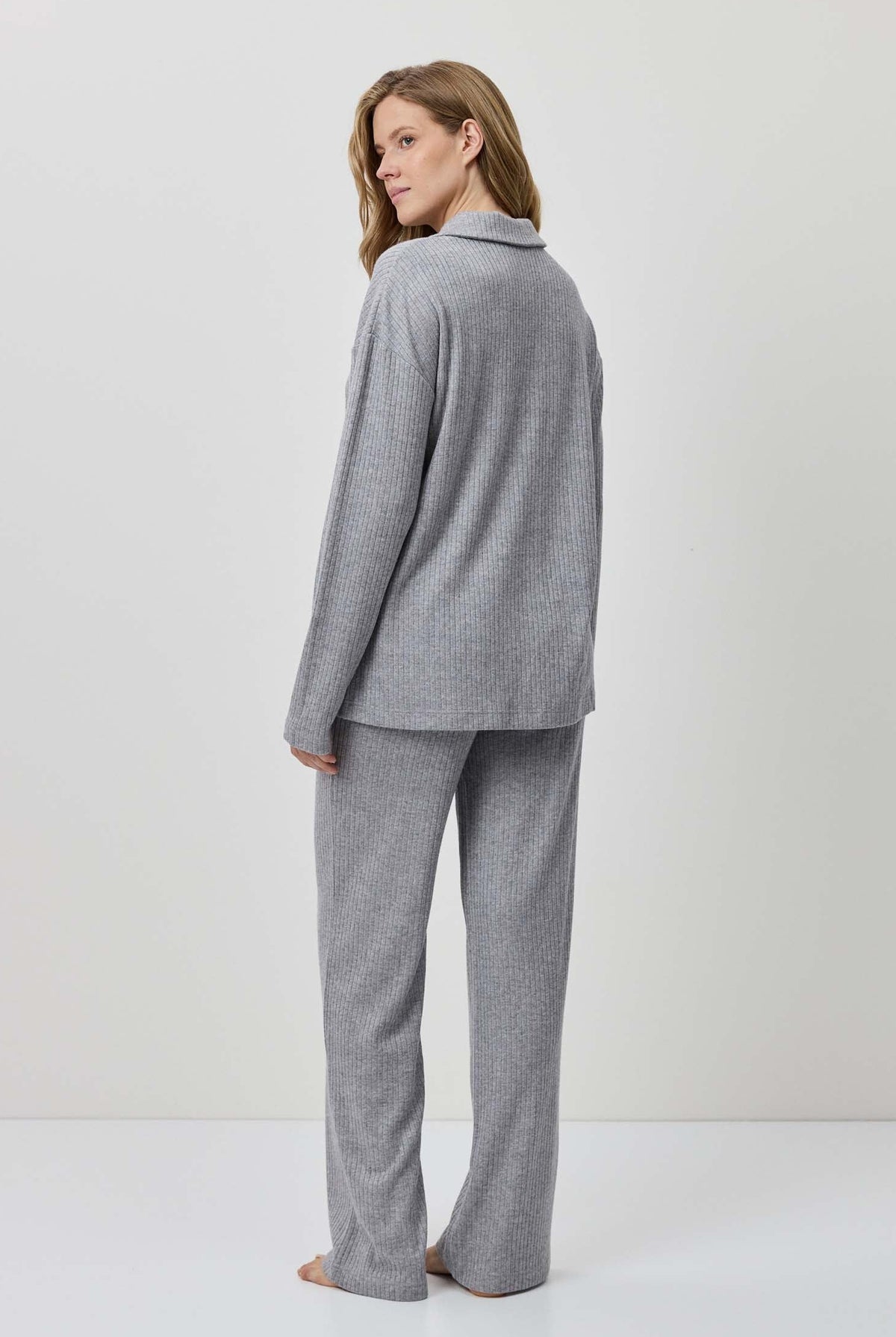 Woman wearing a gray suit standing against a white background