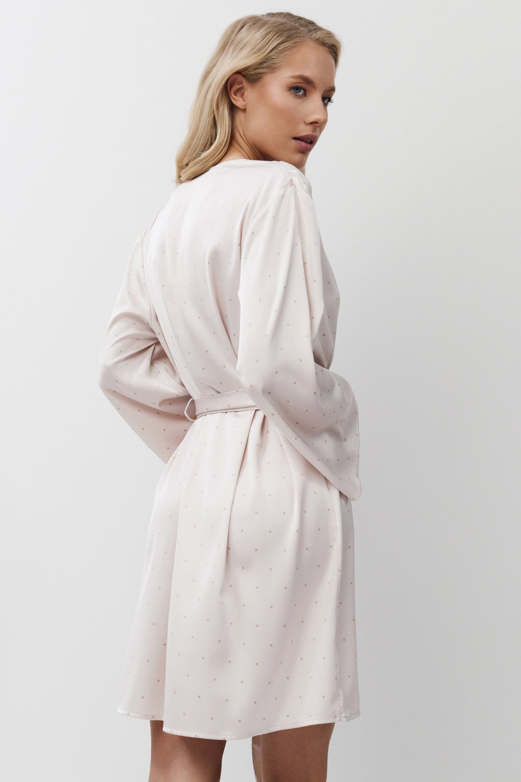 Woman wearing a pink gown against a plain background