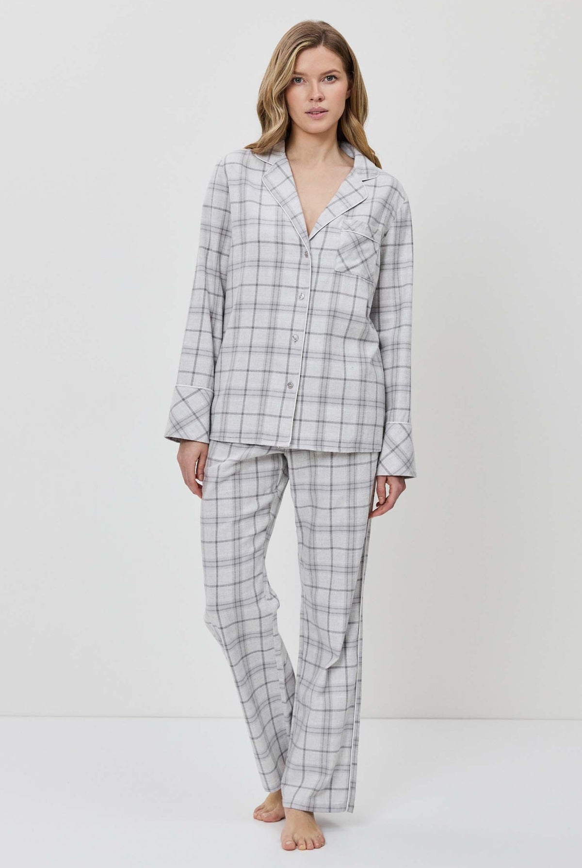 Woman wearing a gray checkered pajama set against a white background