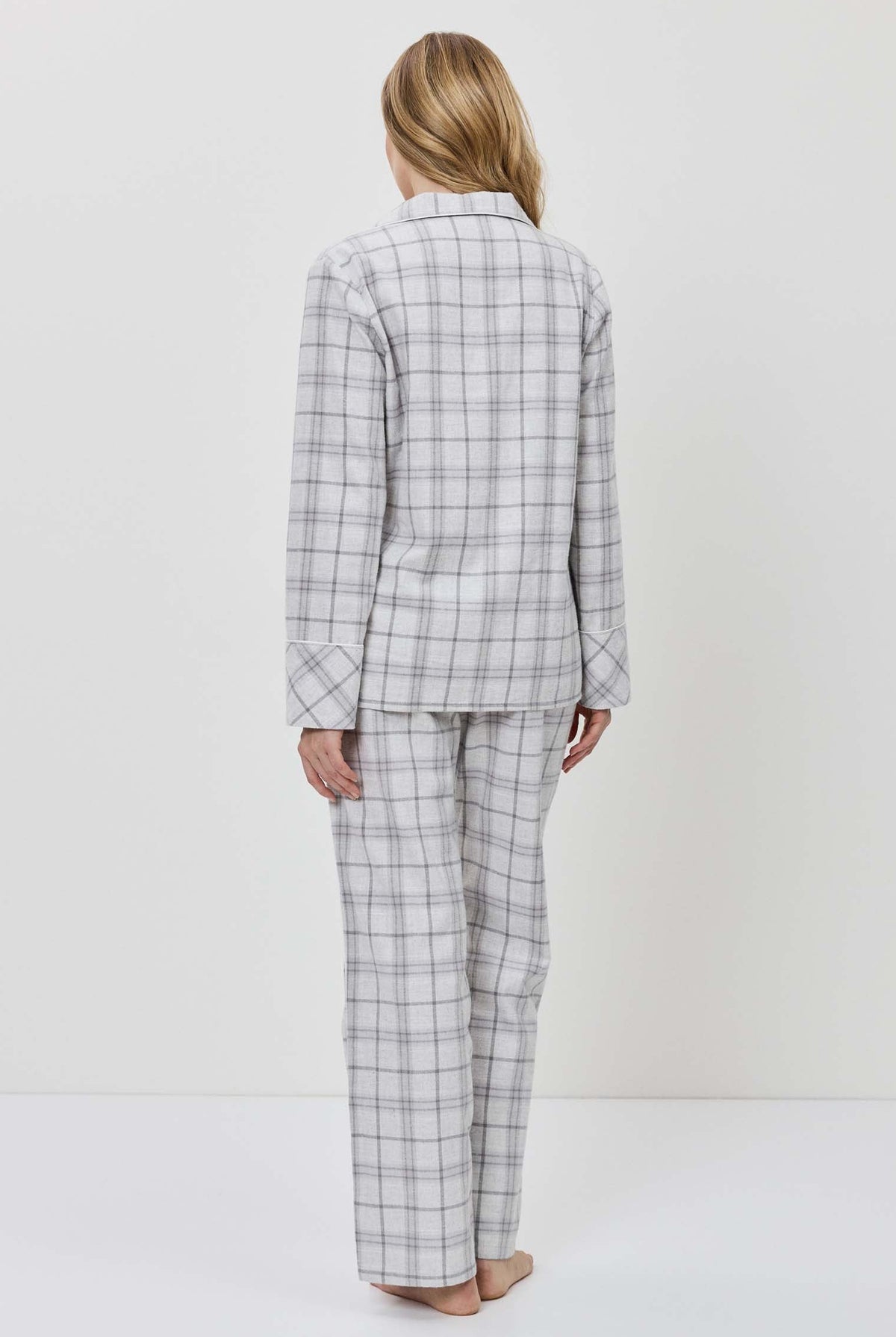 Person wearing a gray checkered suit standing against a white background