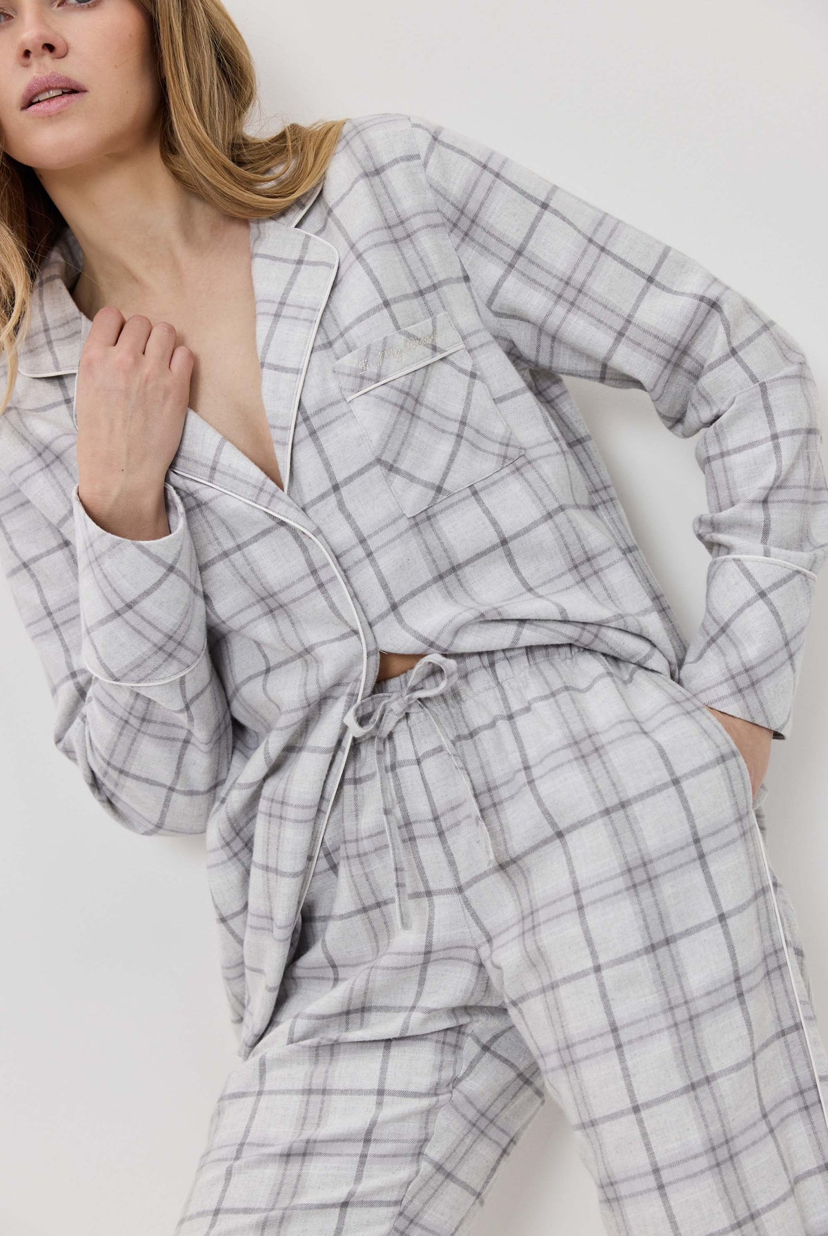 Woman wearing a gray plaid pajama set against a white background