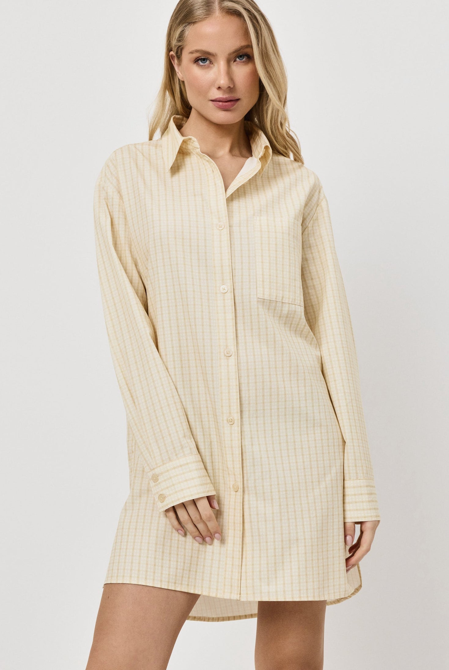 Woman wearing a light yellow ribbed shirt dress on a white background