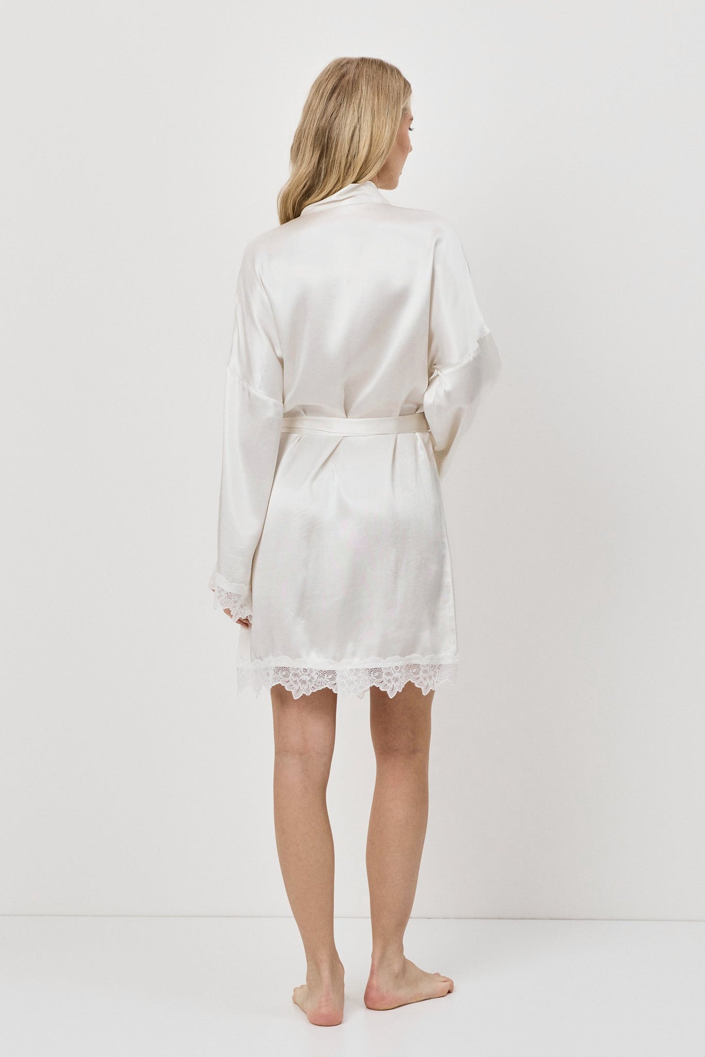 Person wearing a white gown against a plain background