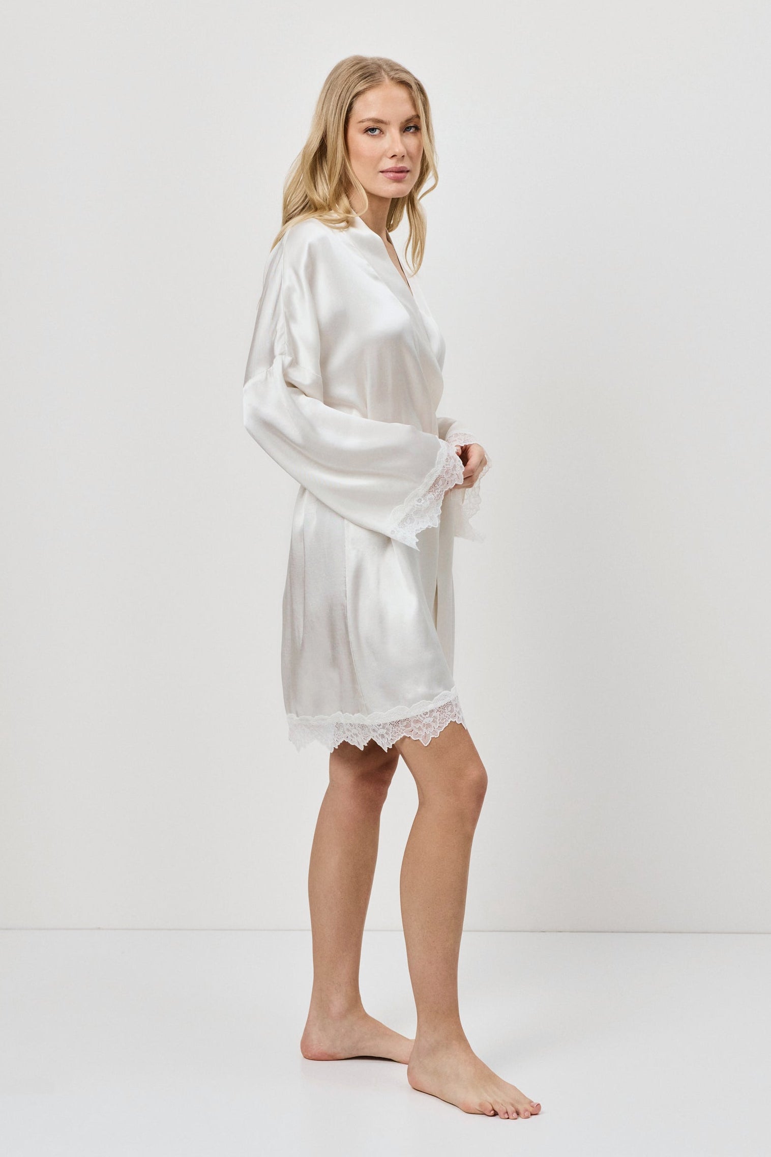 Woman wearing a white gown against a plain background