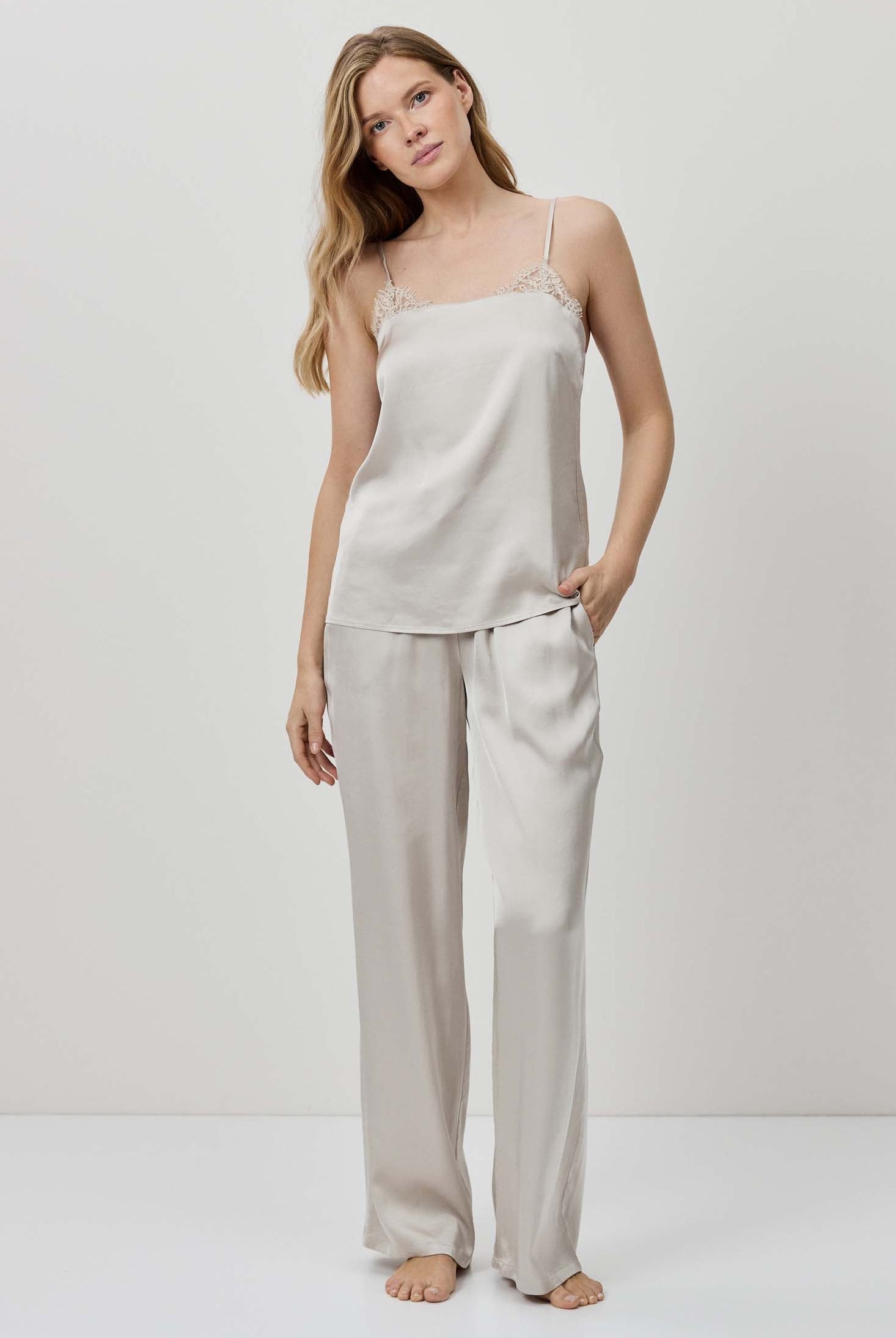 Woman wearing a beige slip dress and pants set on a white background