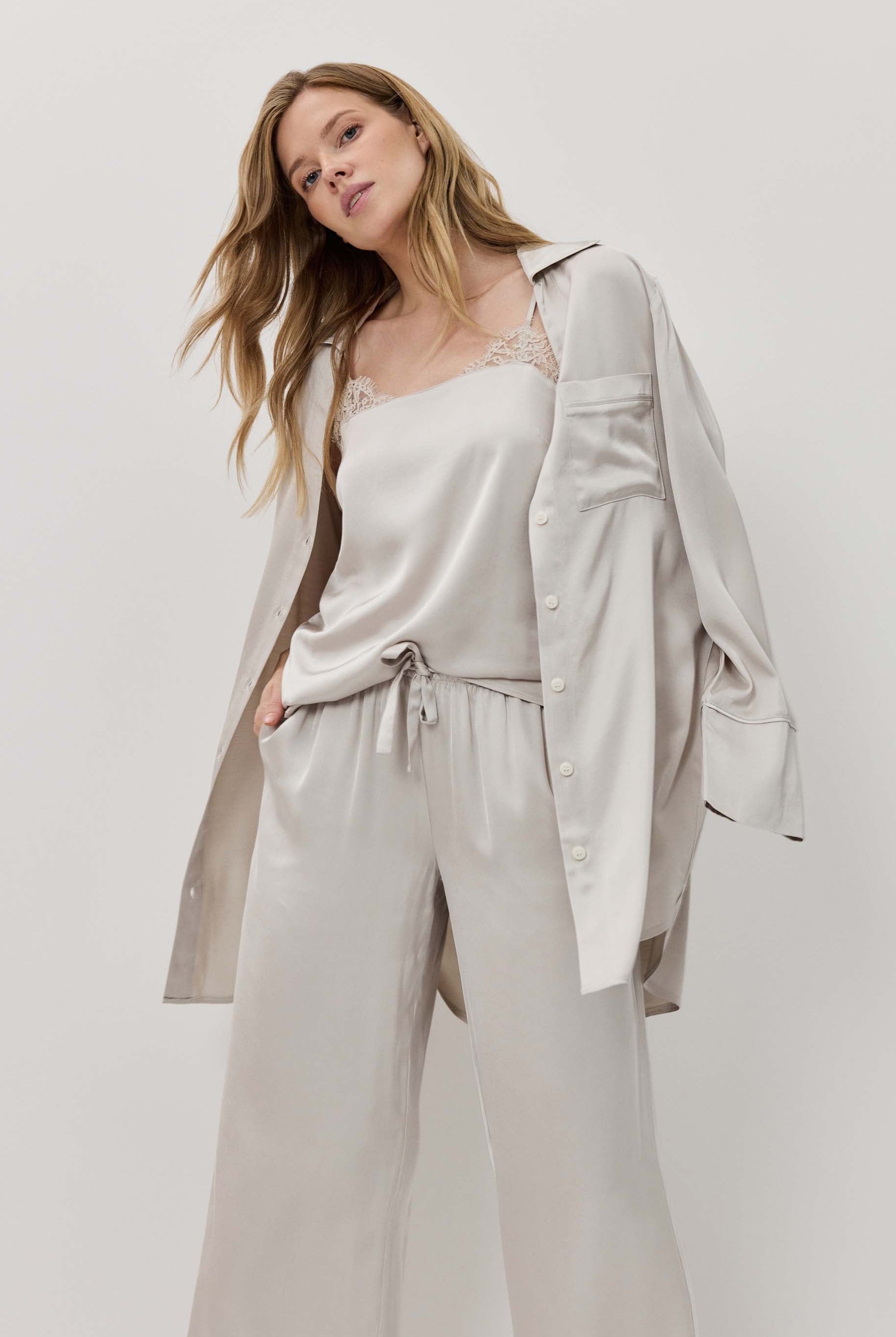 Woman wearing a light gray outfit with a matching jacket on a white background