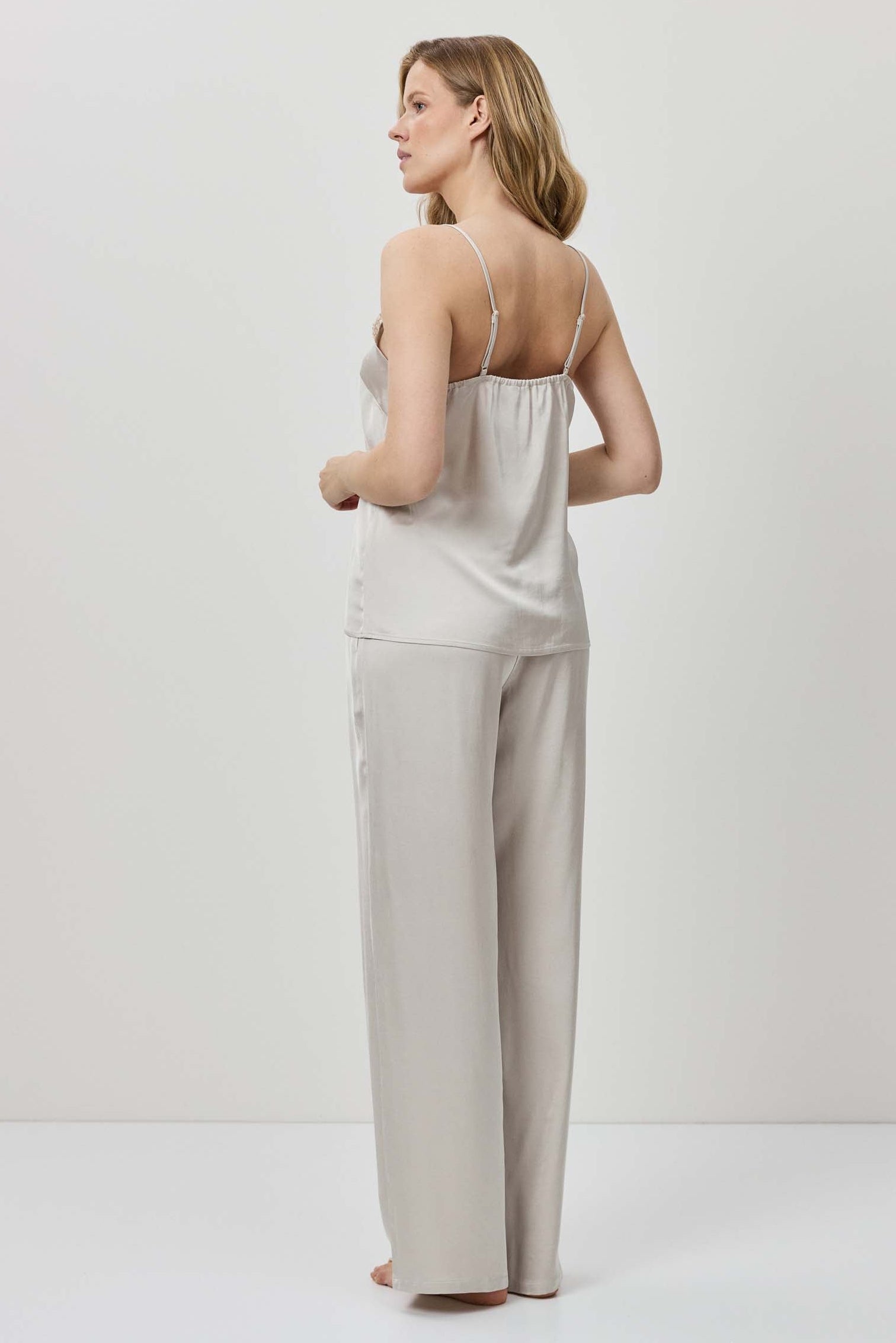 Woman wearing a light-colored jumpsuit on a white background