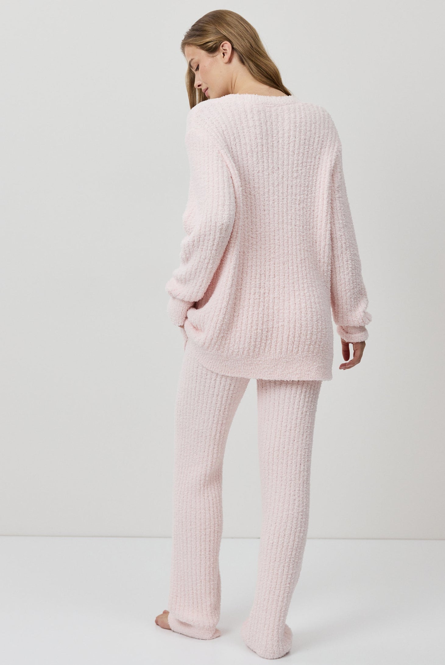 A woman wearing a light pink ribbed knit lounge set.