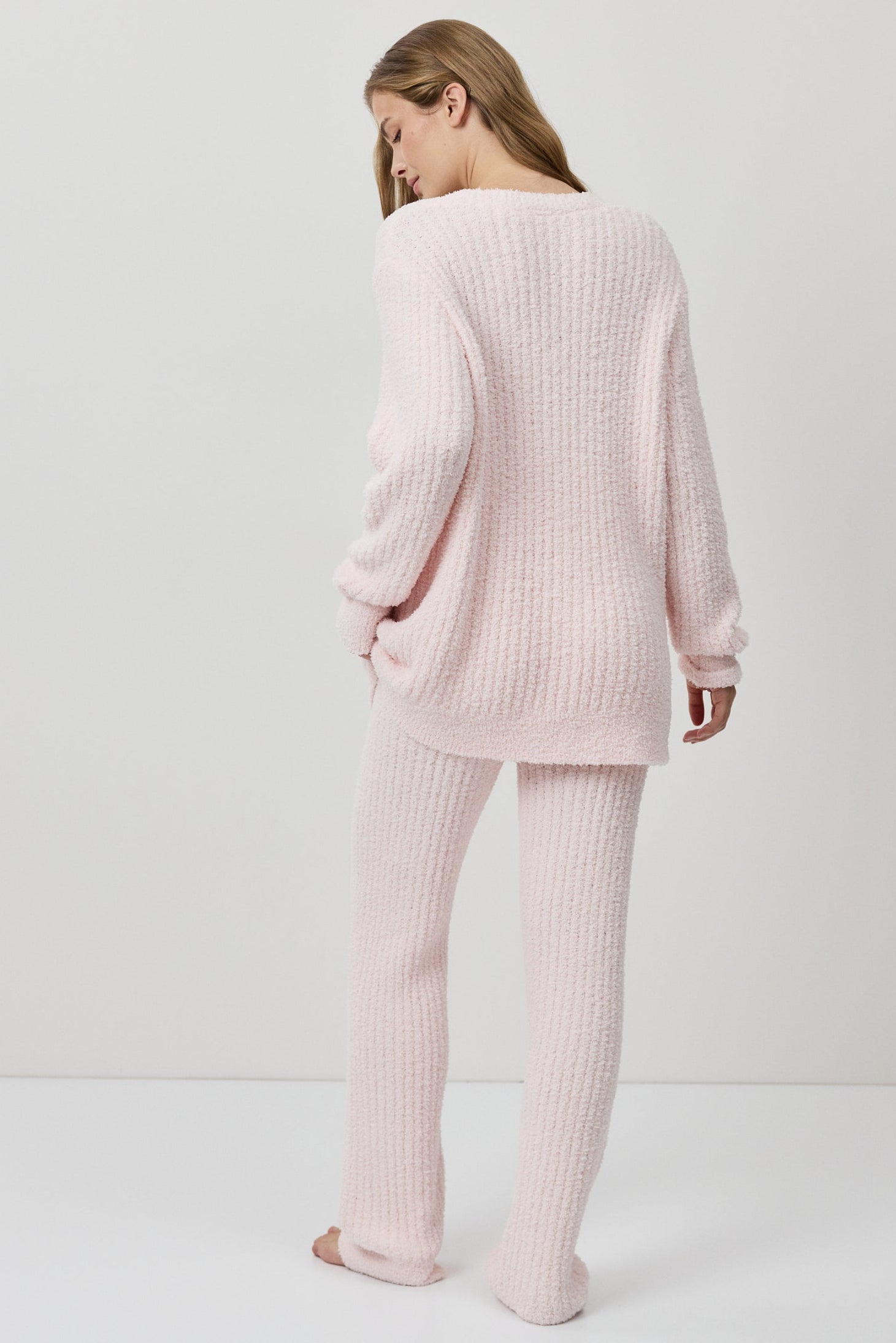 A woman wearing a light pink ribbed knit lounge set.