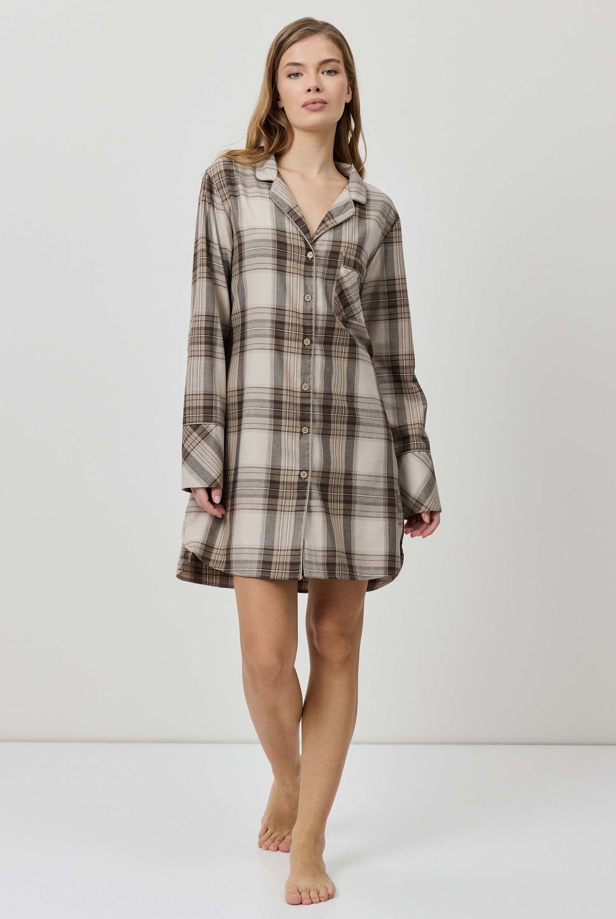 Woman wearing a plaid shirt dress against a white background