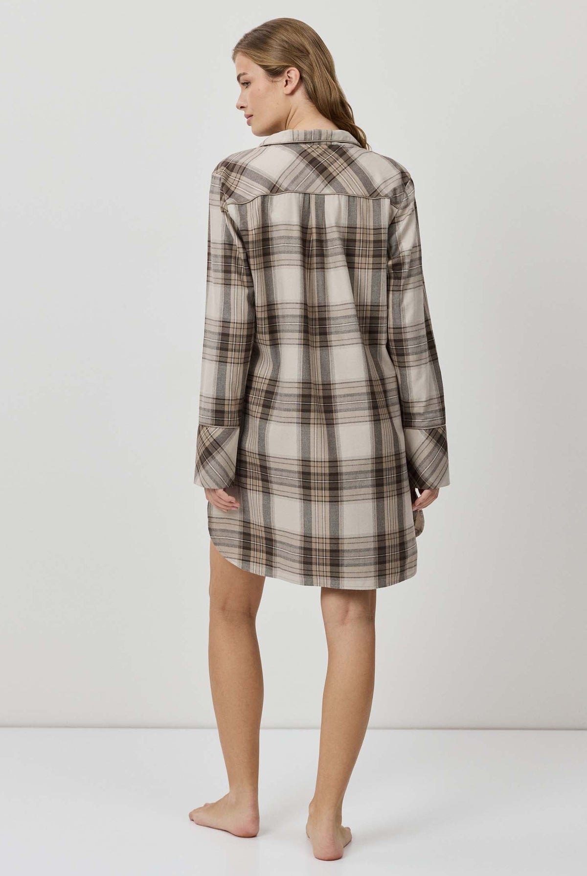 Woman wearing a plaid shirt dress against a white background