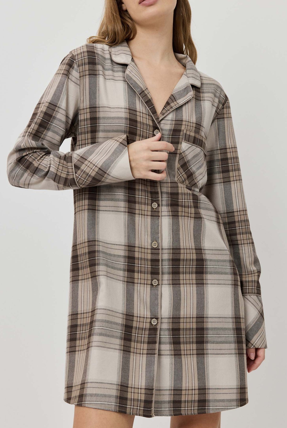 Woman wearing a plaid dress against a plain background