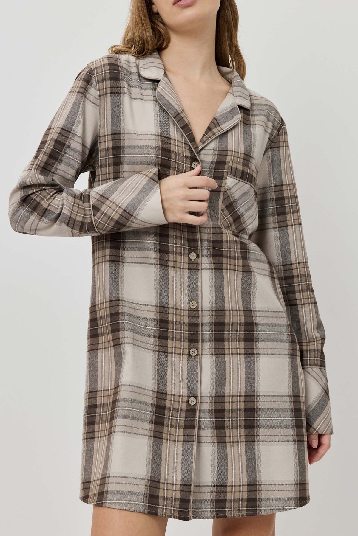 Woman wearing a plaid dress against a plain background