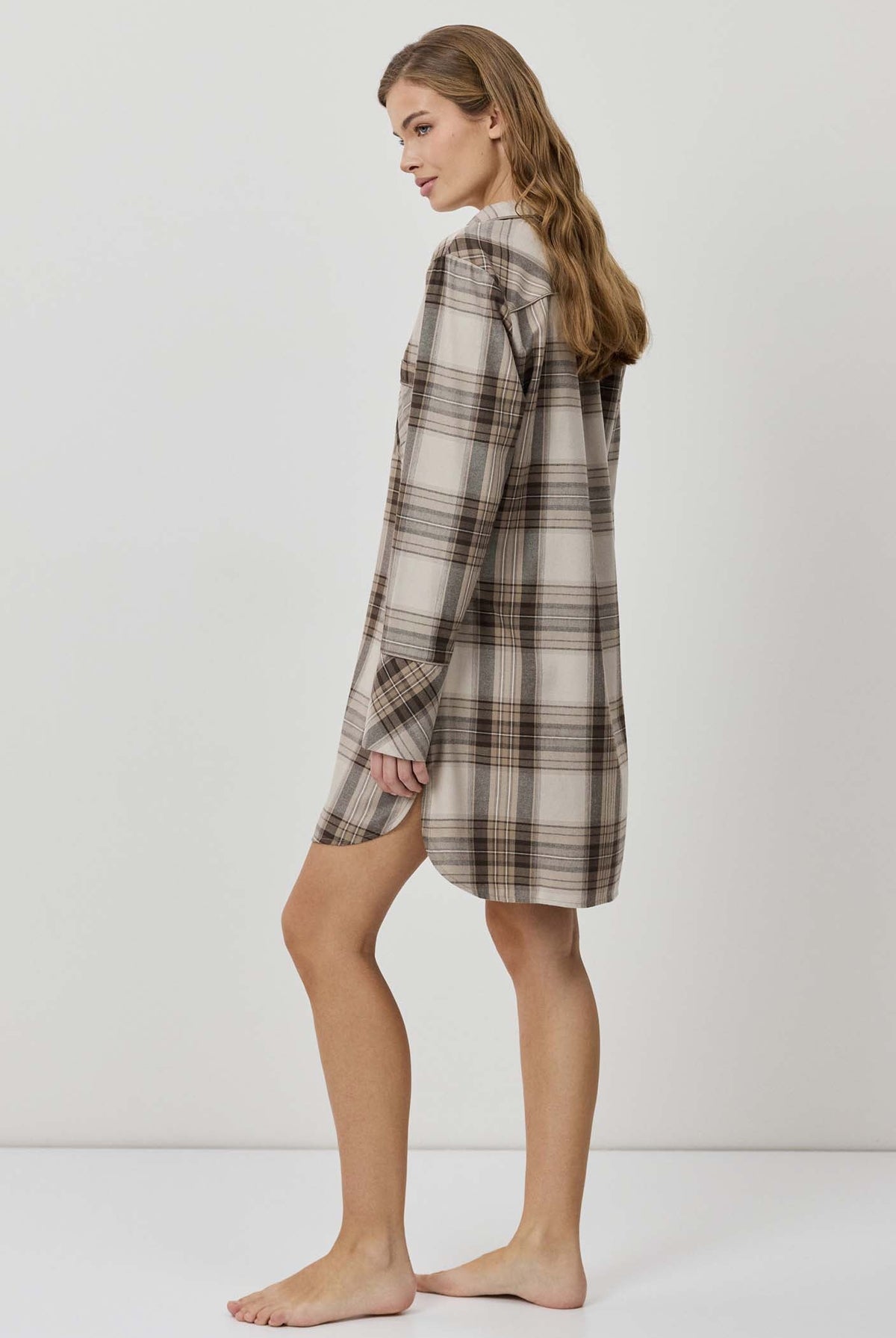 Woman wearing a plaid shirt dress against a white background