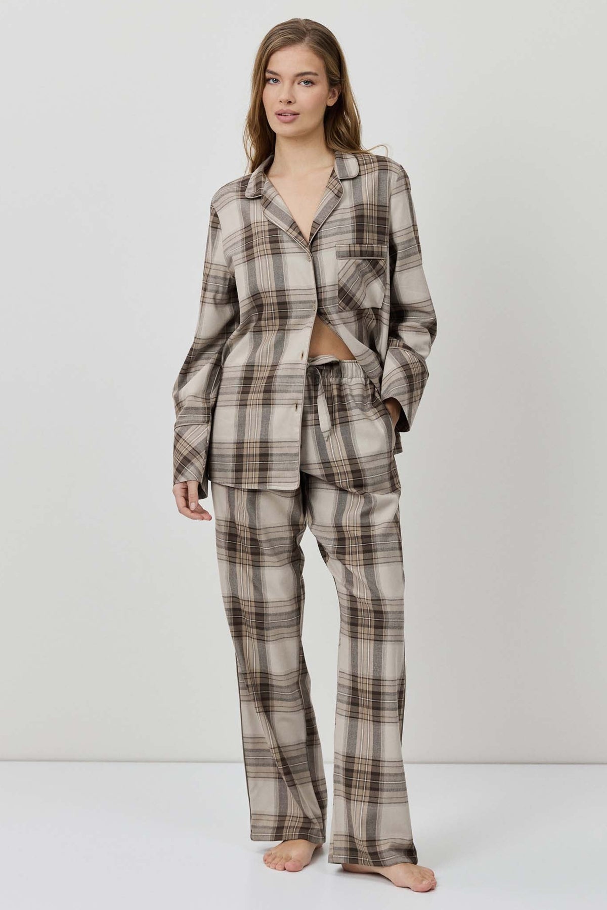 Woman wearing a plaid pajama set against a white background