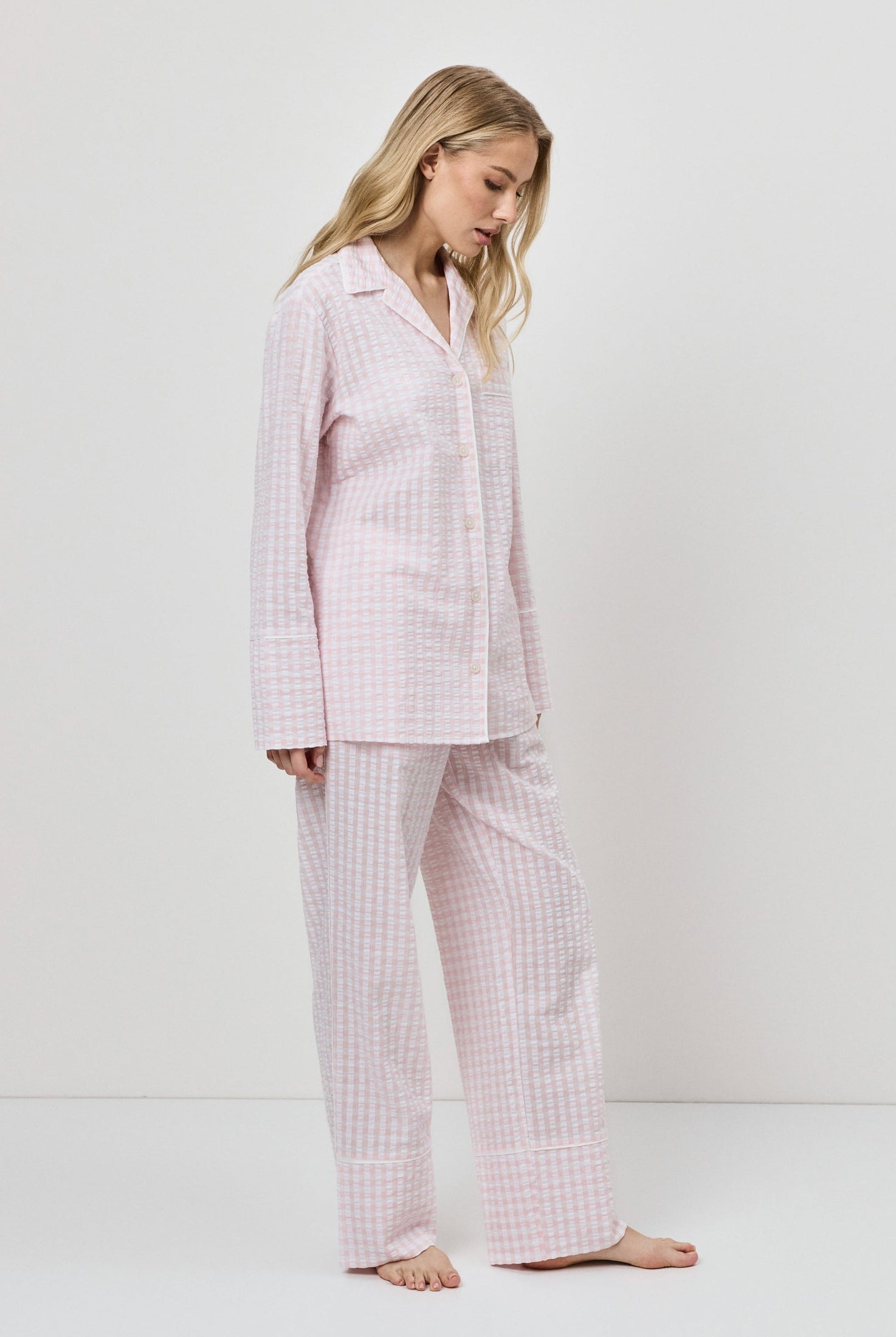 Woman wearing a pink checkered pajama set against a white background