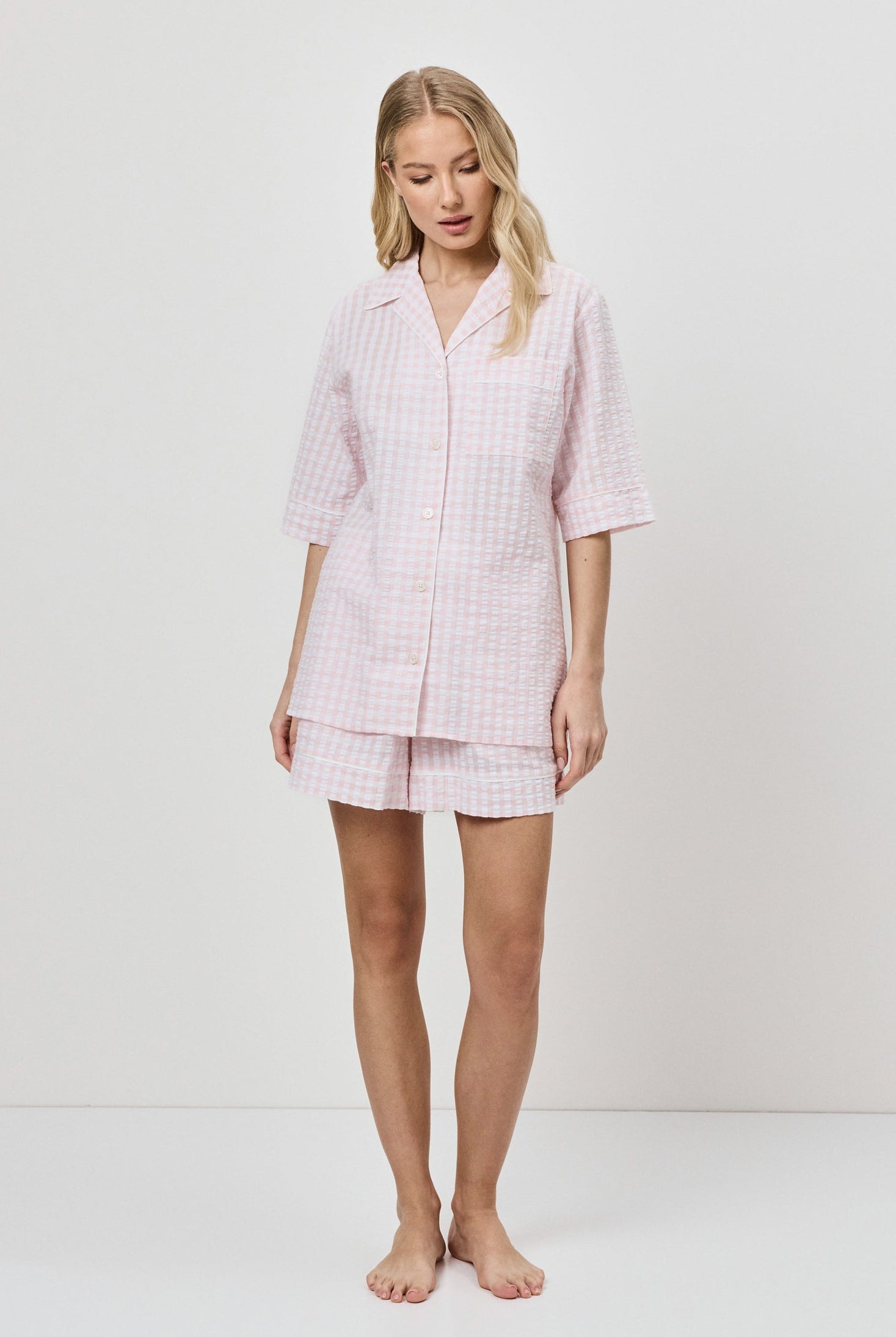 Woman wearing a pink checkered pajama set on a white background