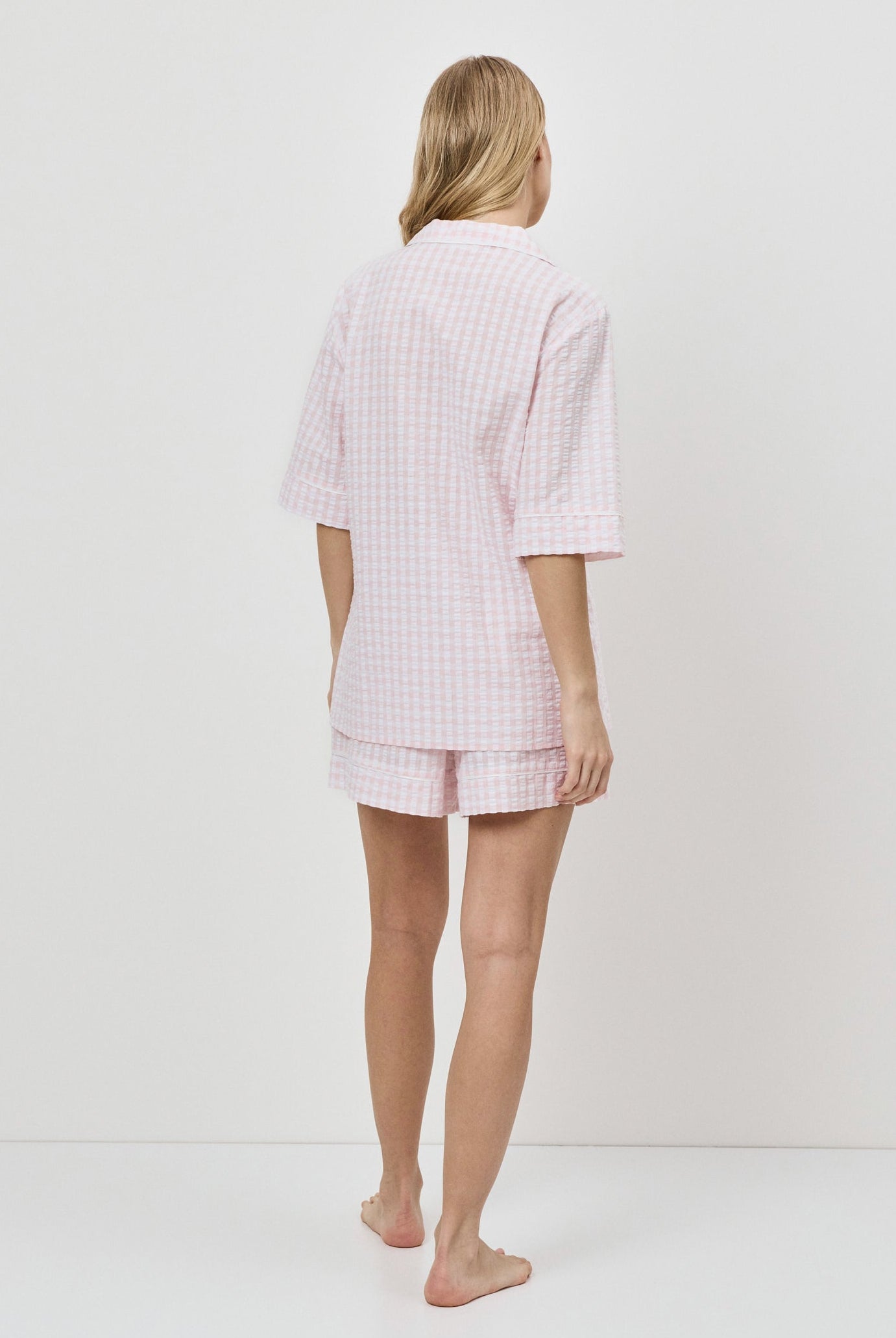 Woman wearing a pink checkered pajama set on a white background