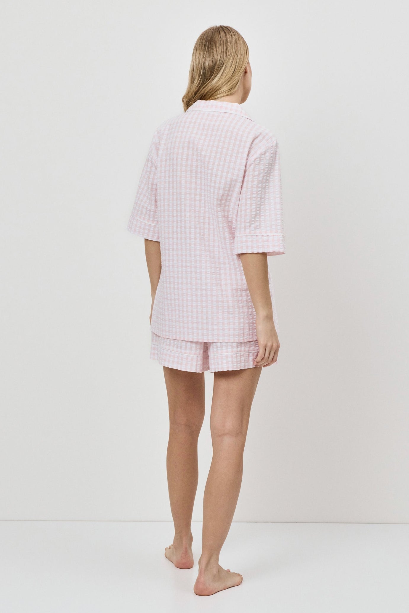 Woman wearing a pink checkered pajama set on a white background