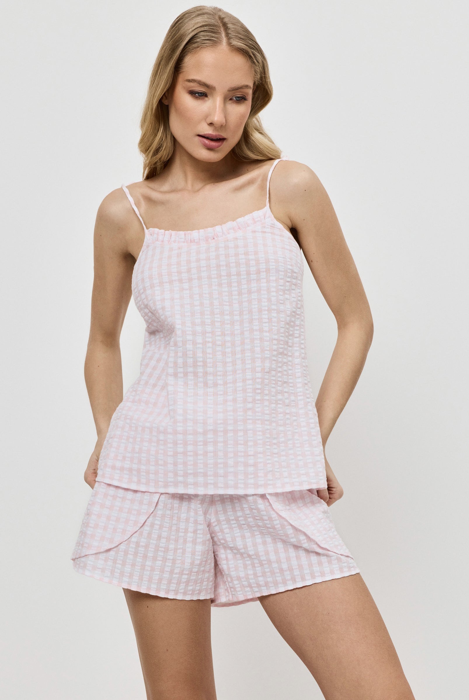Woman wearing a pink checkered pajama set against a white background