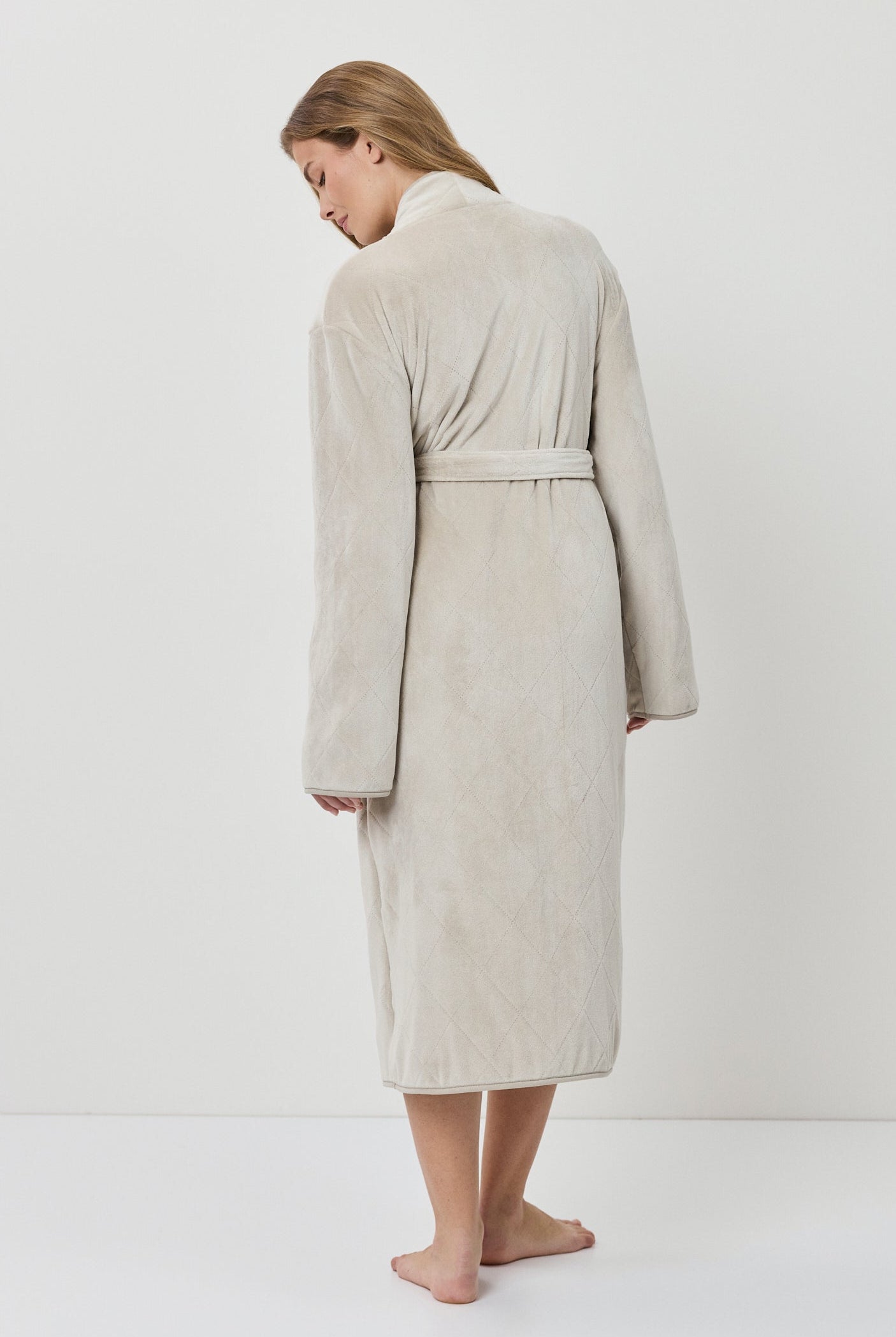 Woman wearing a beige robe against a white background