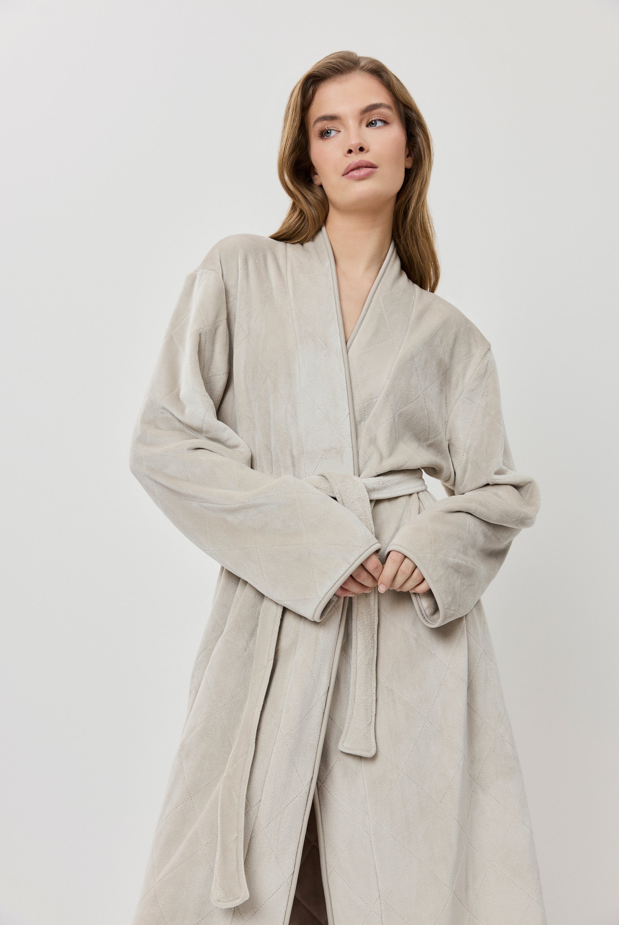 Woman wearing a beige robe against a white background