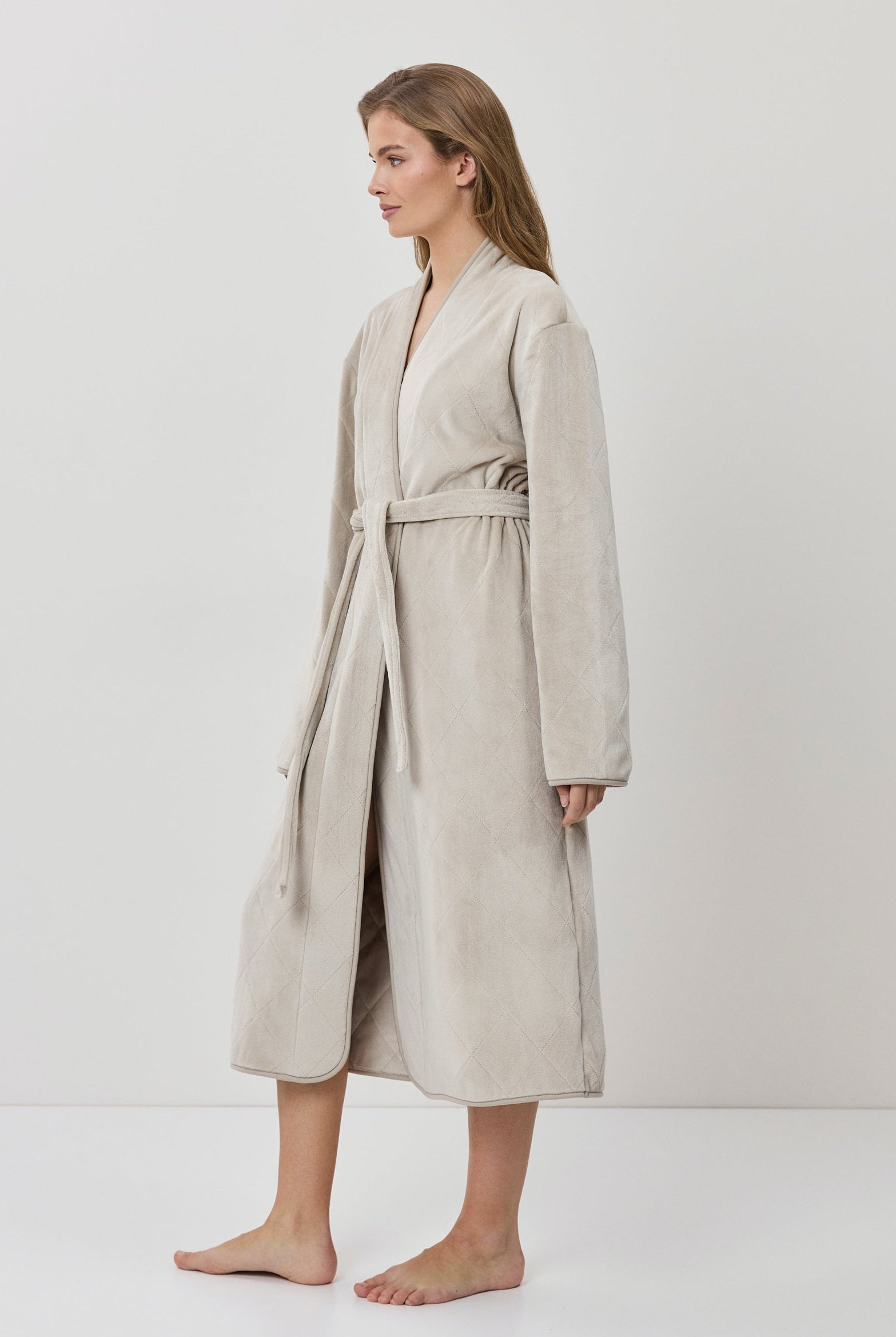 Woman wearing a beige robe against a white background