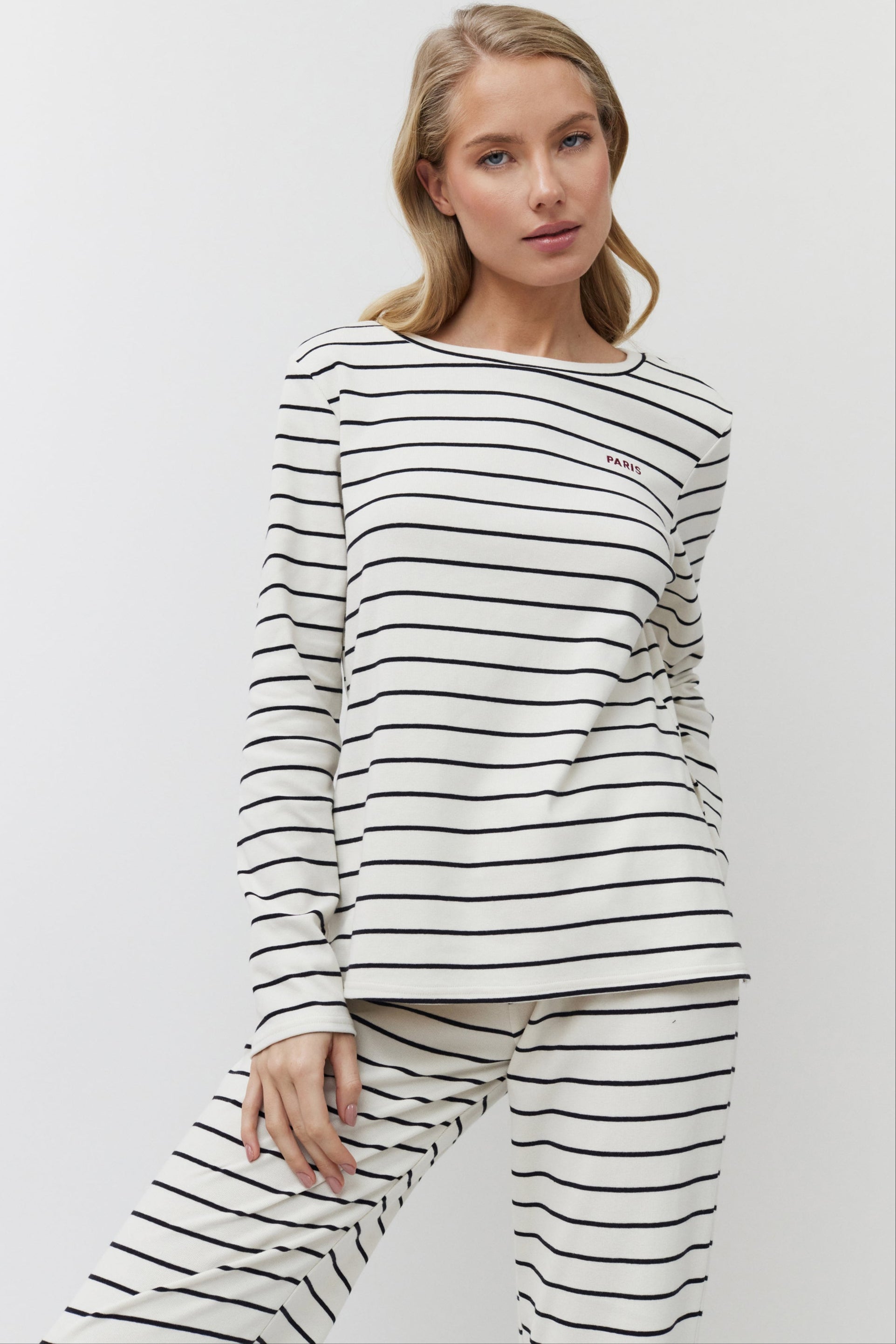 Woman wearing a black and white striped long-sleeve top and pants on a white background