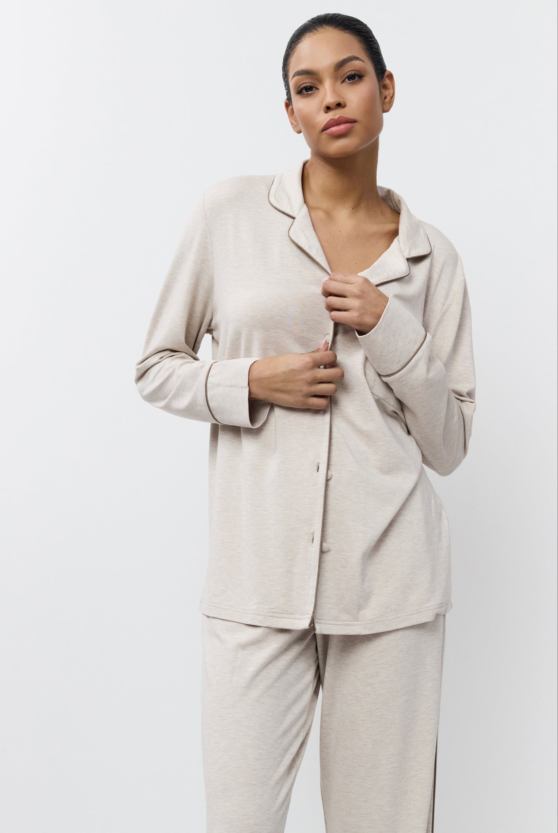 Woman wearing beige pajama set against a white background