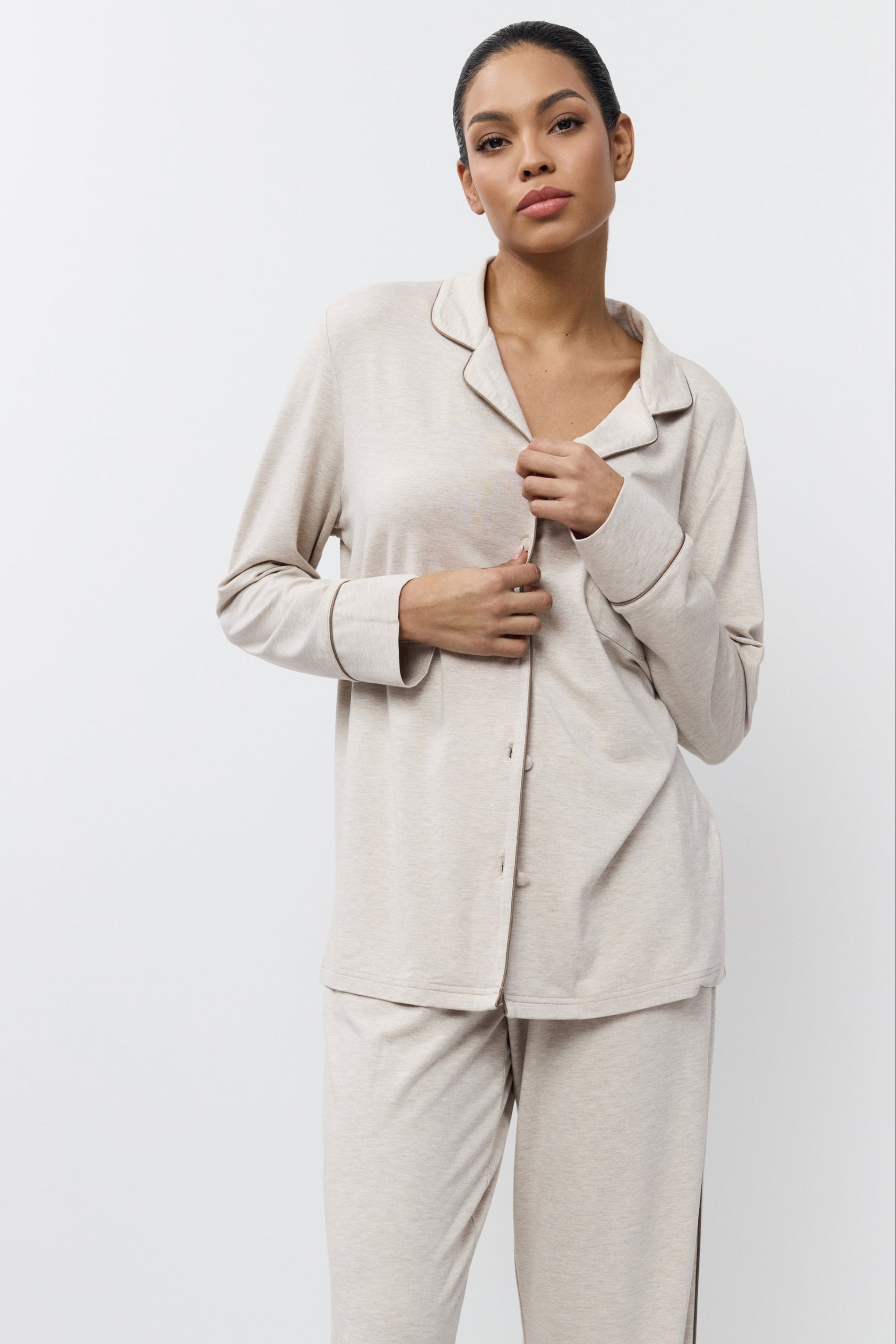 Woman wearing beige pajama set against a white background
