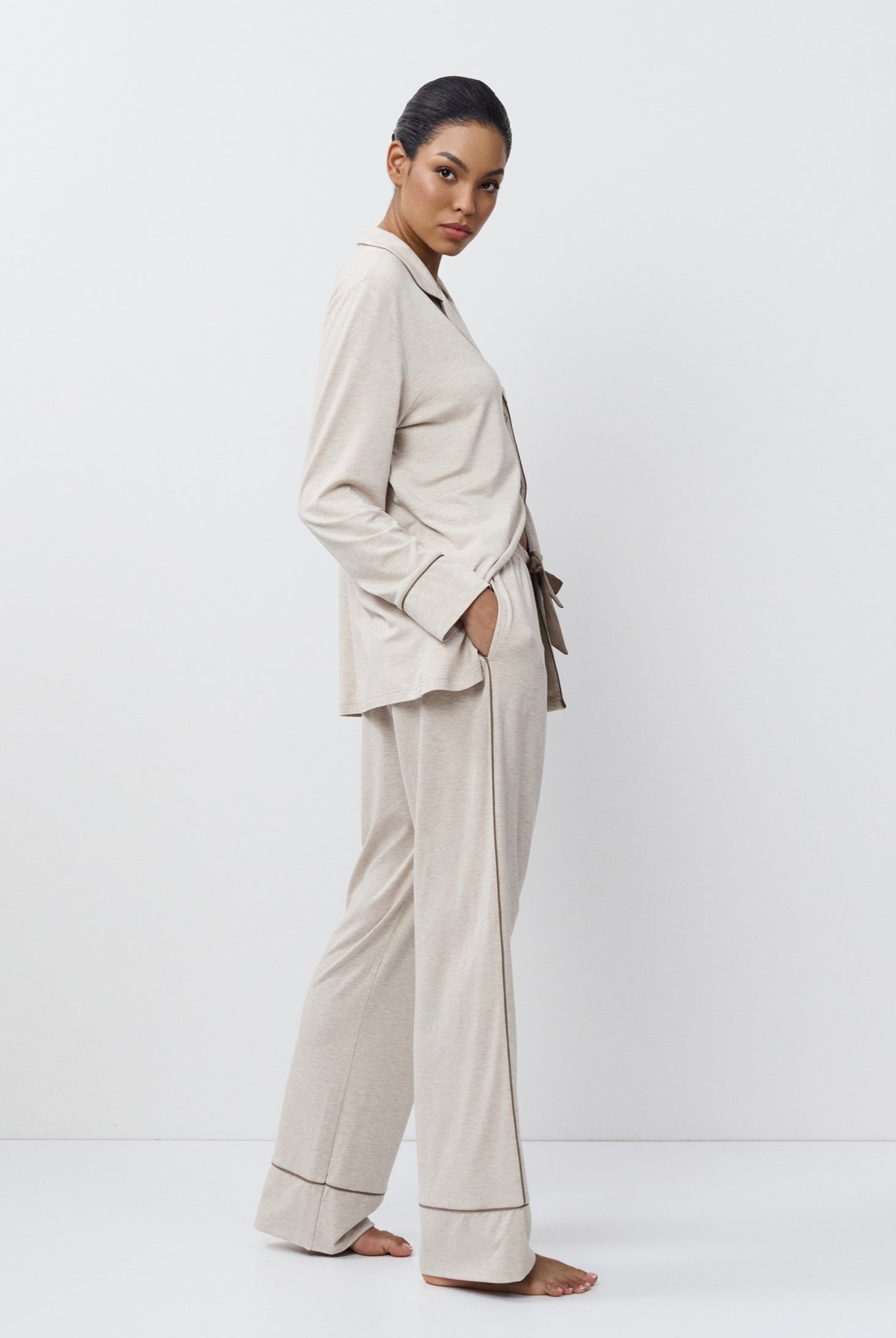 Woman wearing a beige set standing against a white background