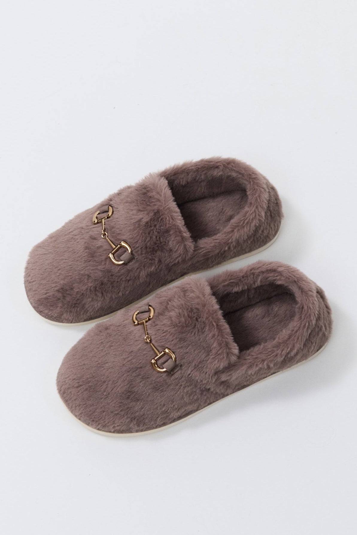 Pair of brown slippers with a decorative buckle on a light gray background