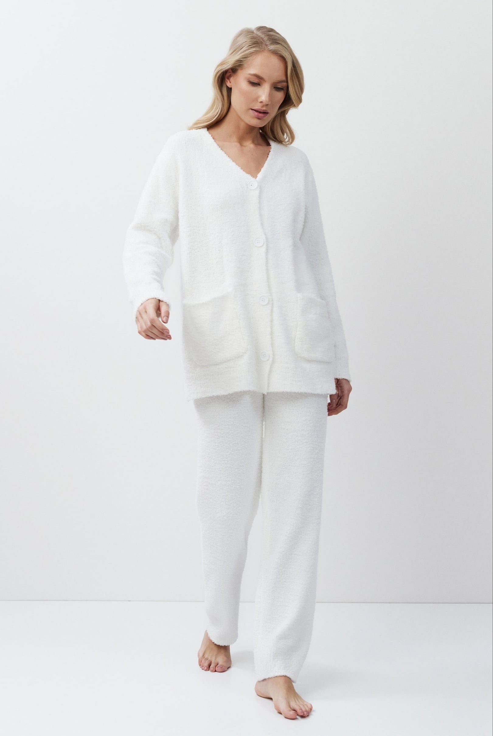 Woman wearing a white loungewear set on a plain background