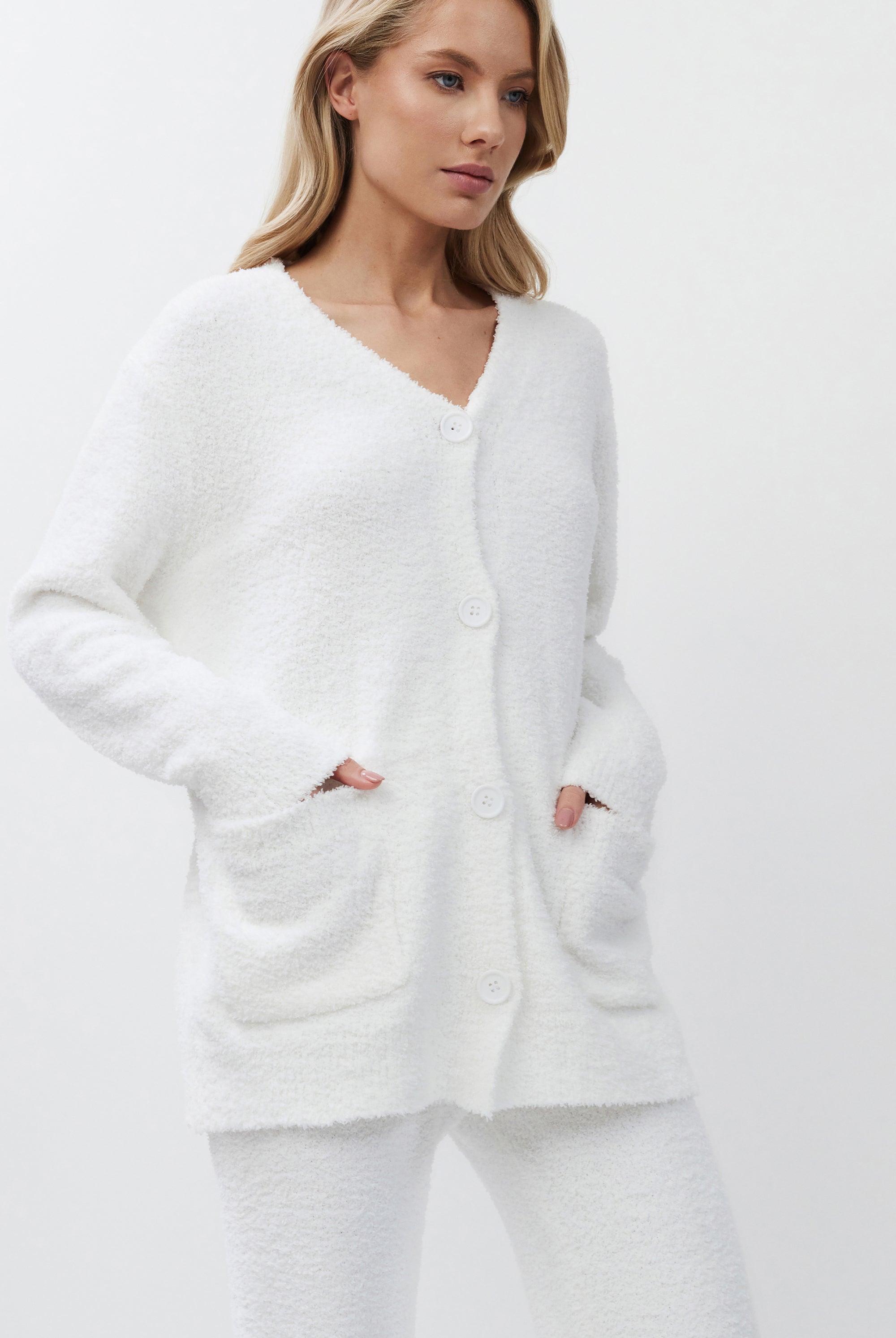 Woman wearing a white cardigan on a plain background