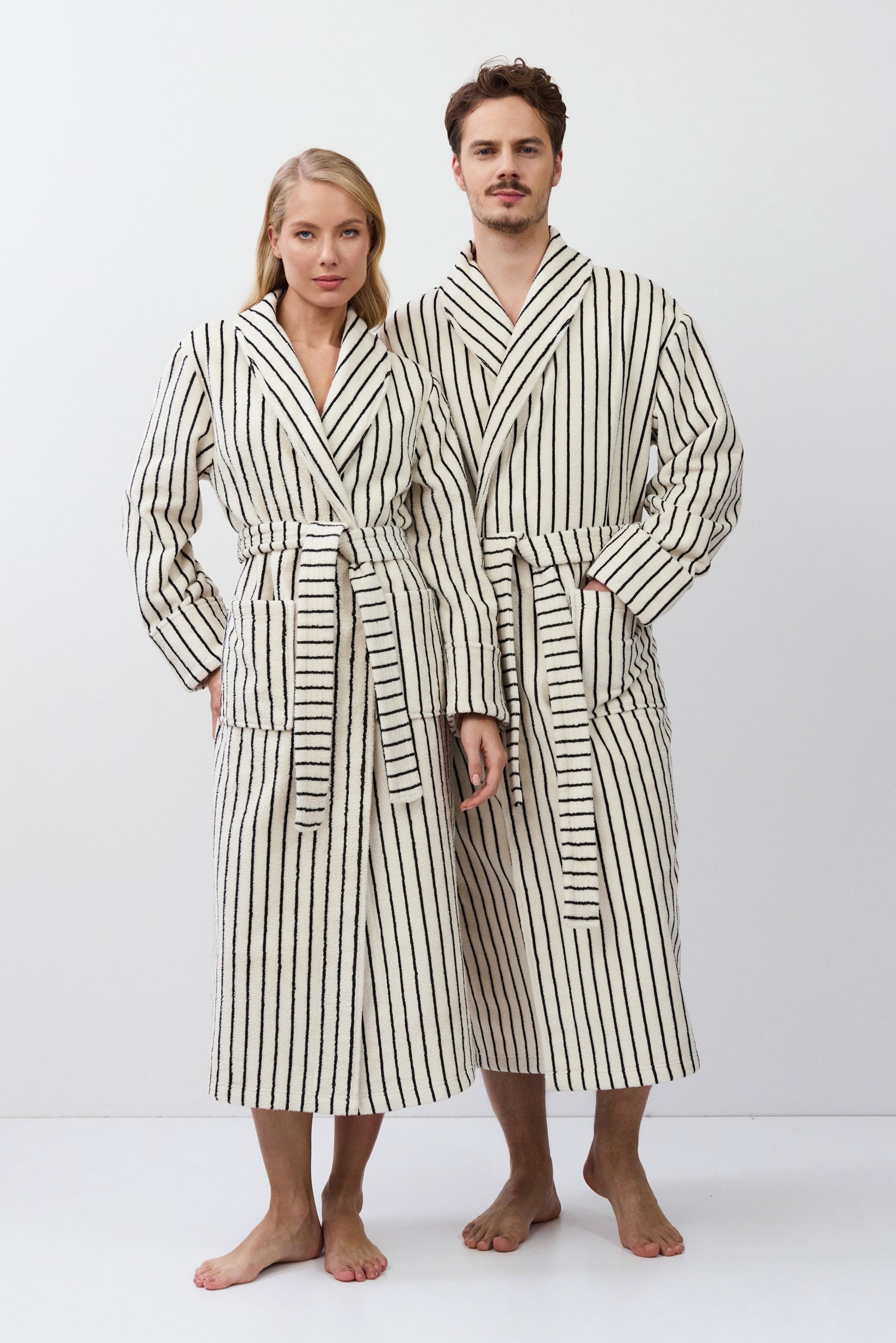 Two people wearing matching striped bathrobes on a white background