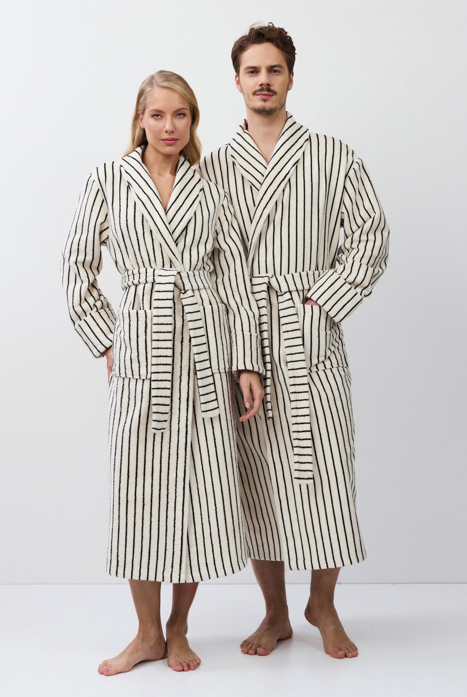 Two people wearing matching striped bathrobes on a white background