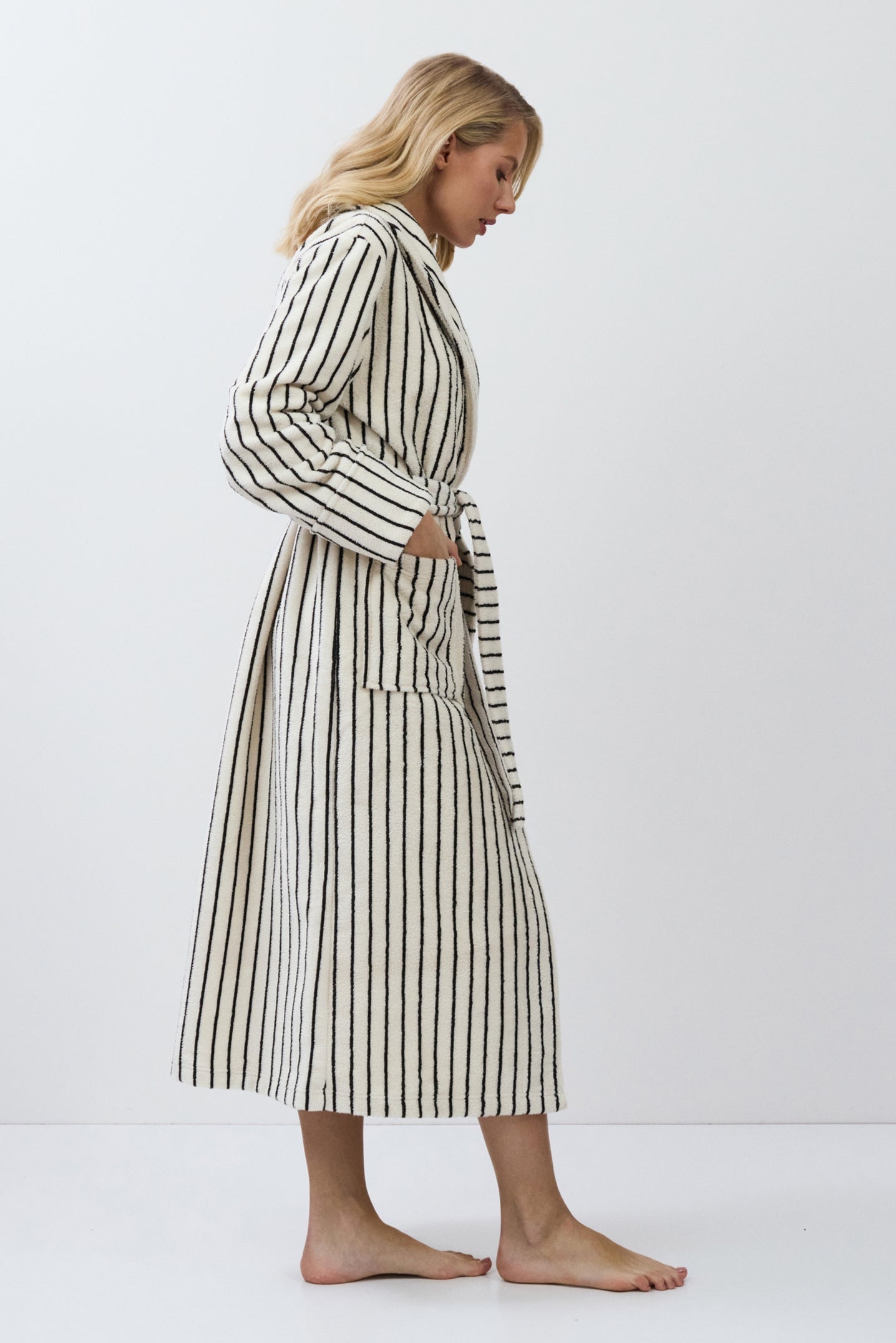 Woman wearing a striped bathrobe on a white background