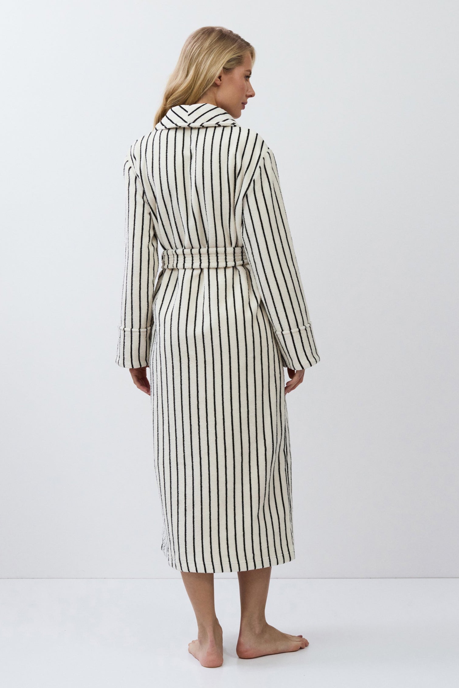 Woman wearing a striped bathrobe against a white background