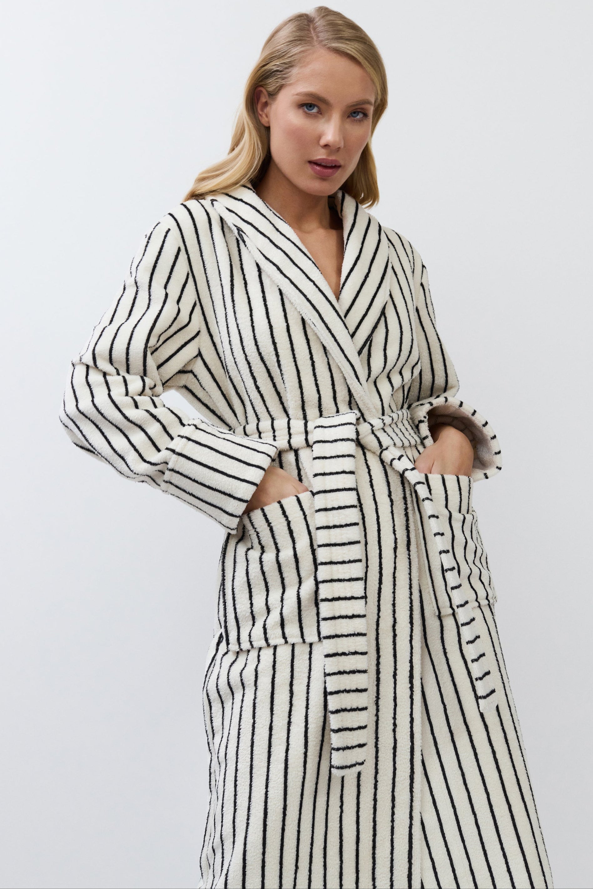 Woman wearing a black and white striped robe against a plain background