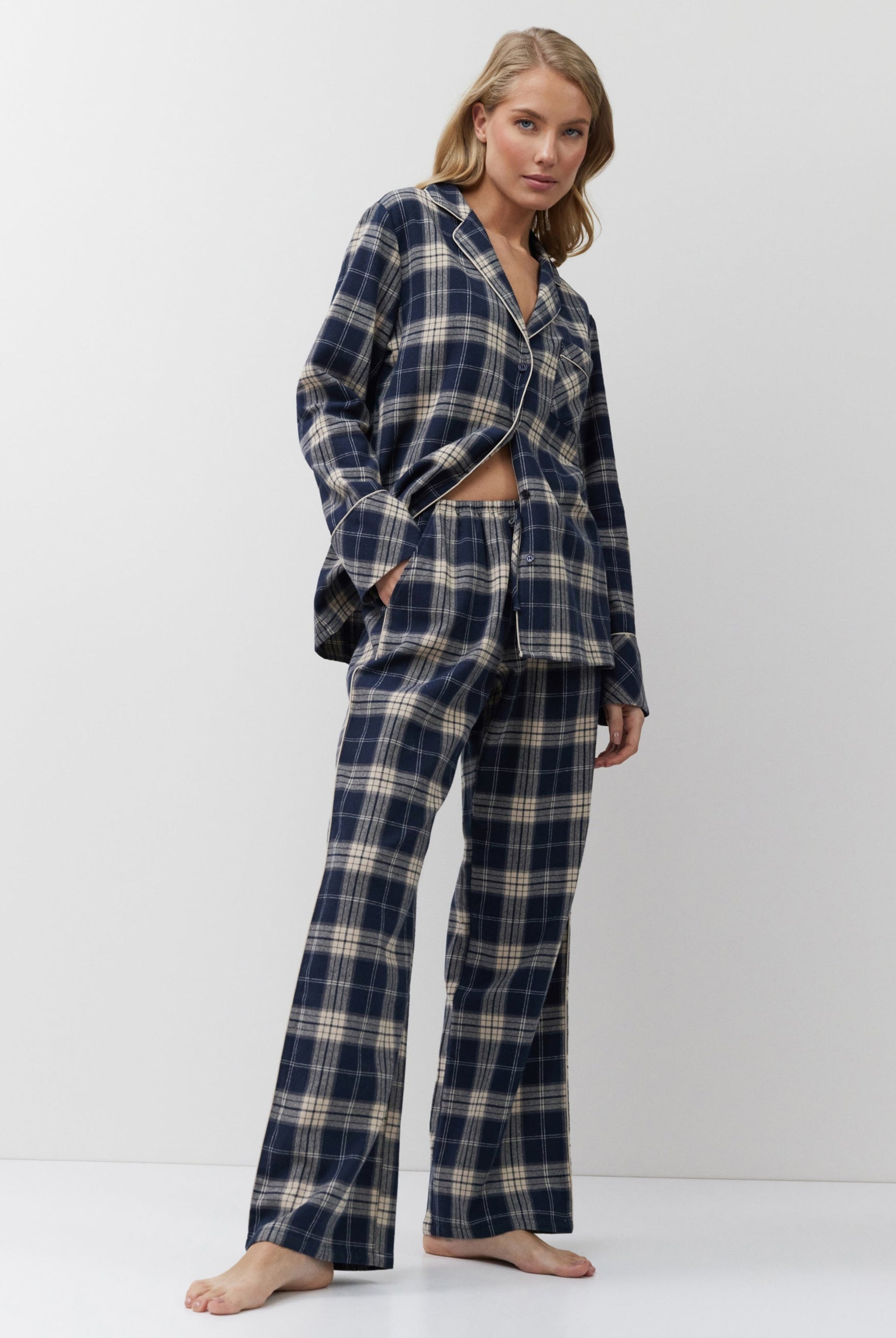 Woman wearing a navy and beige plaid pajama set on a white background