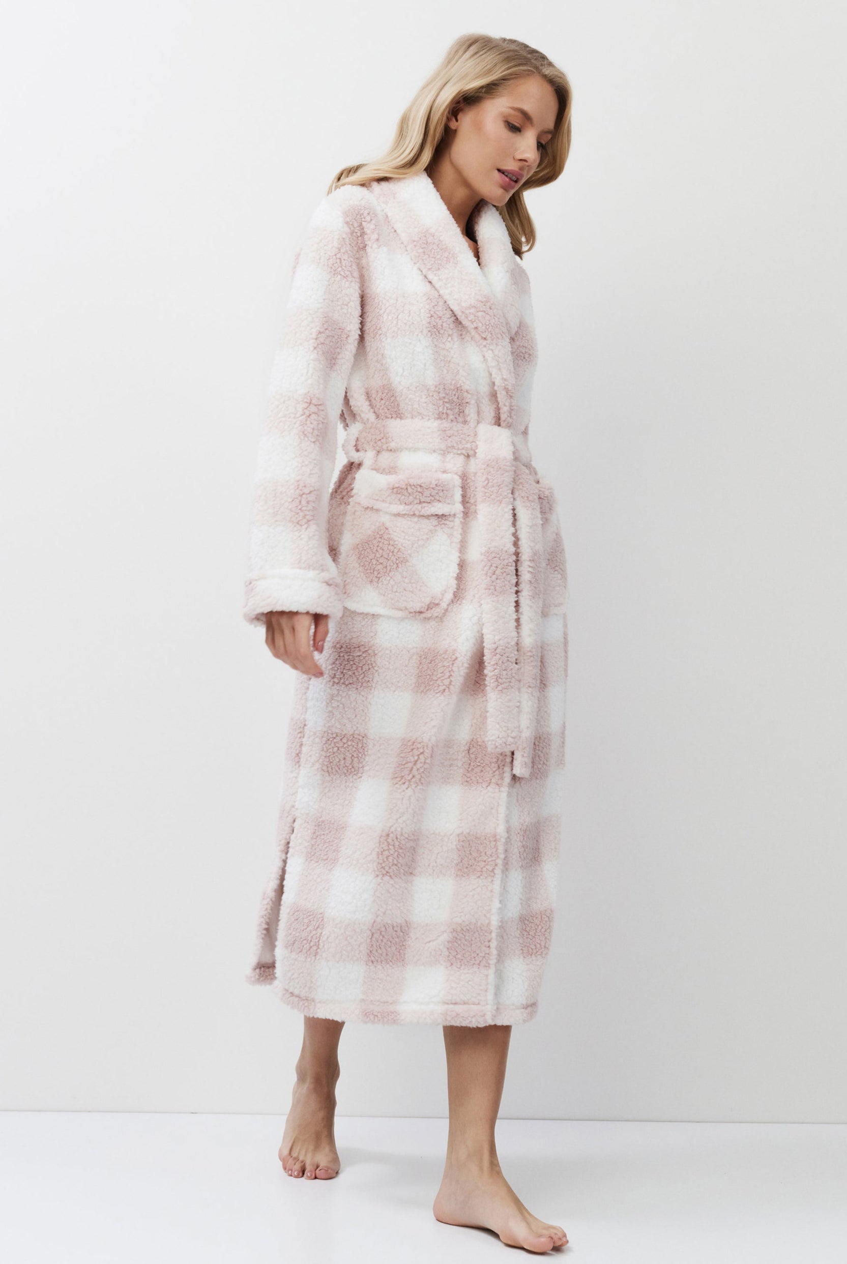 Woman wearing a pink and white checkered bathrobe on a white background