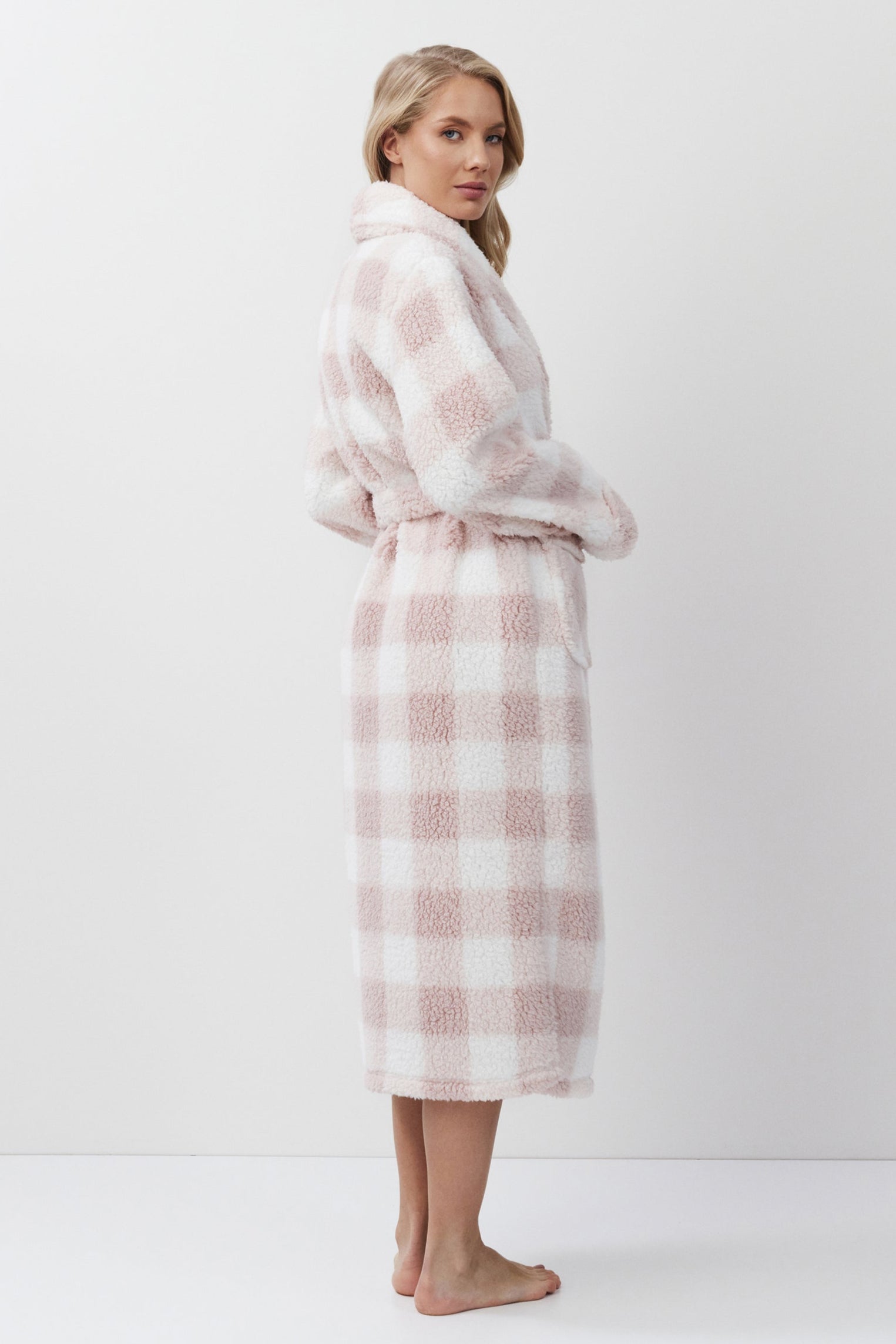 Woman wearing a pink and white checkered bathrobe on a white background