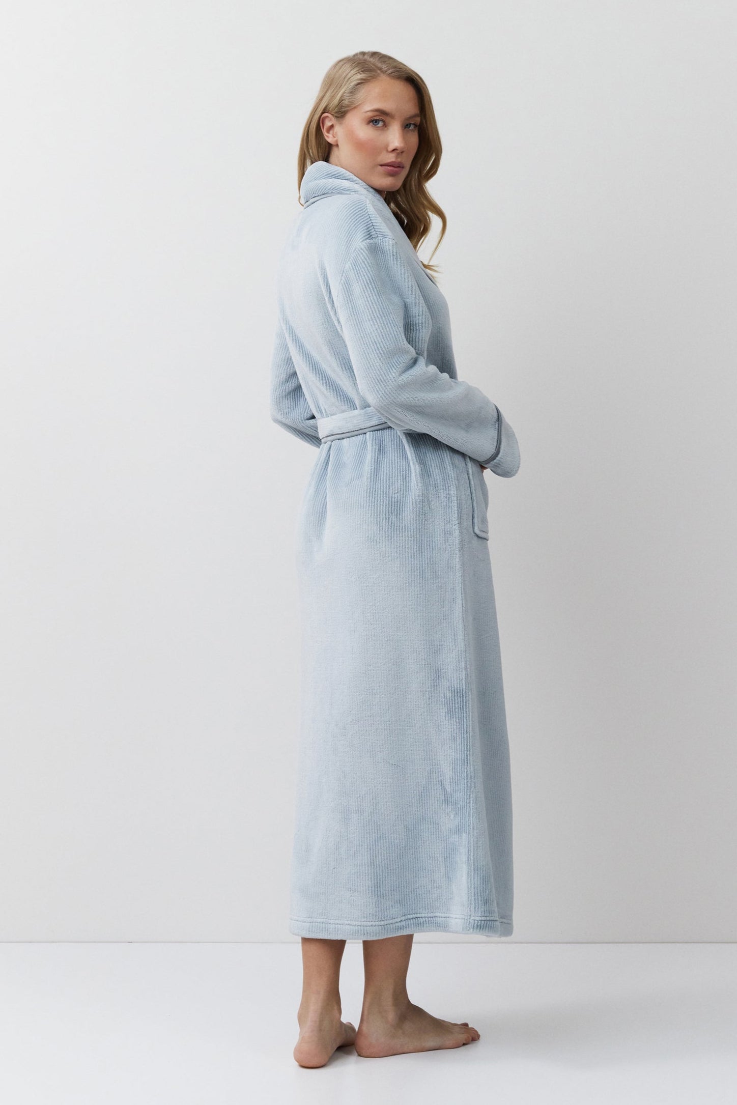 Woman wearing a light blue bathrobe against a white background