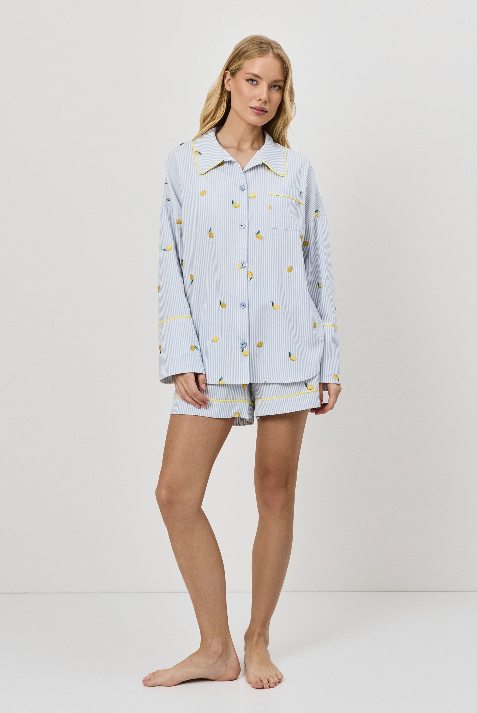 Woman wearing a light blue pajama set with a lemon embroideries on a white background