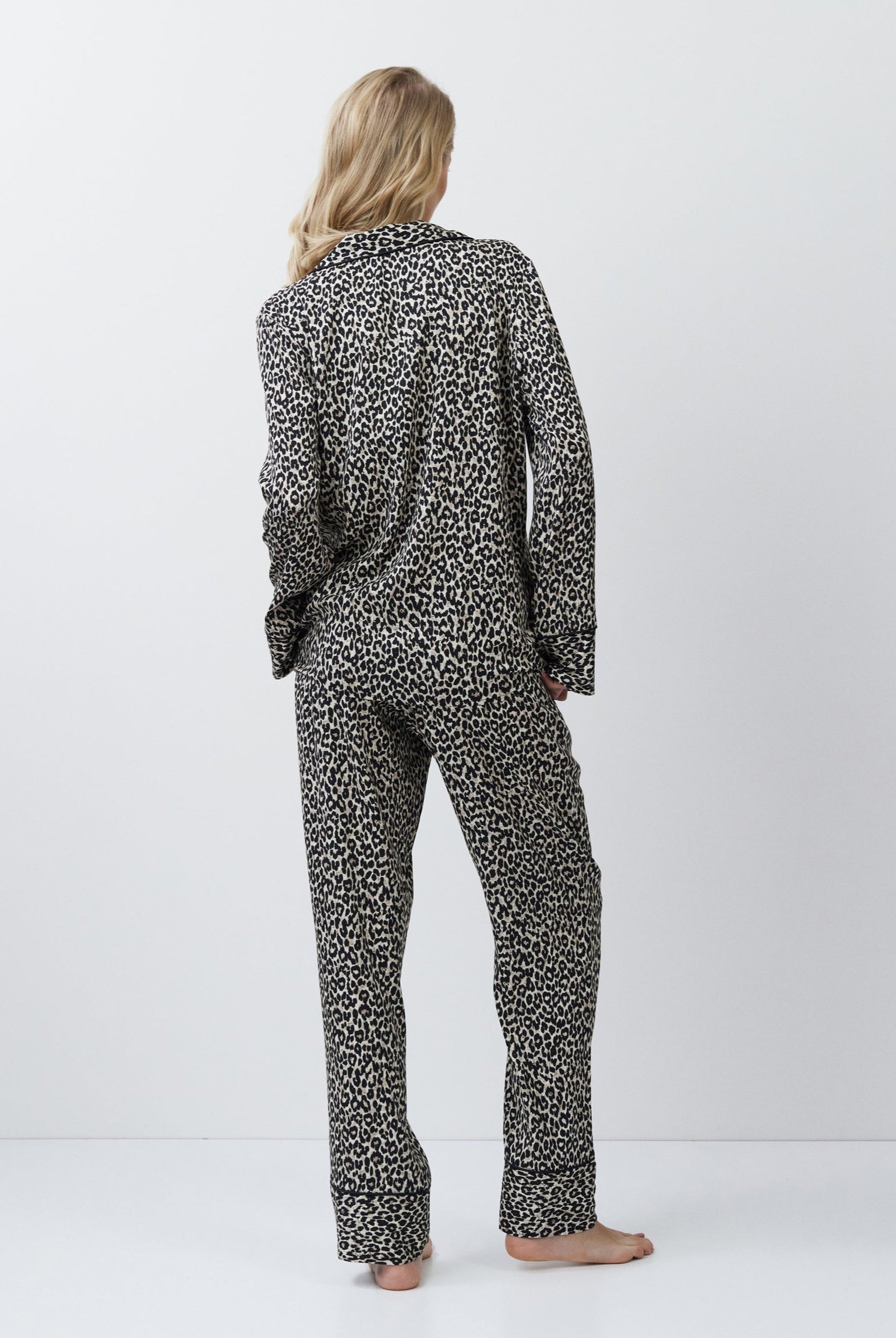 Person wearing a leopard patterned pajama set on a white background