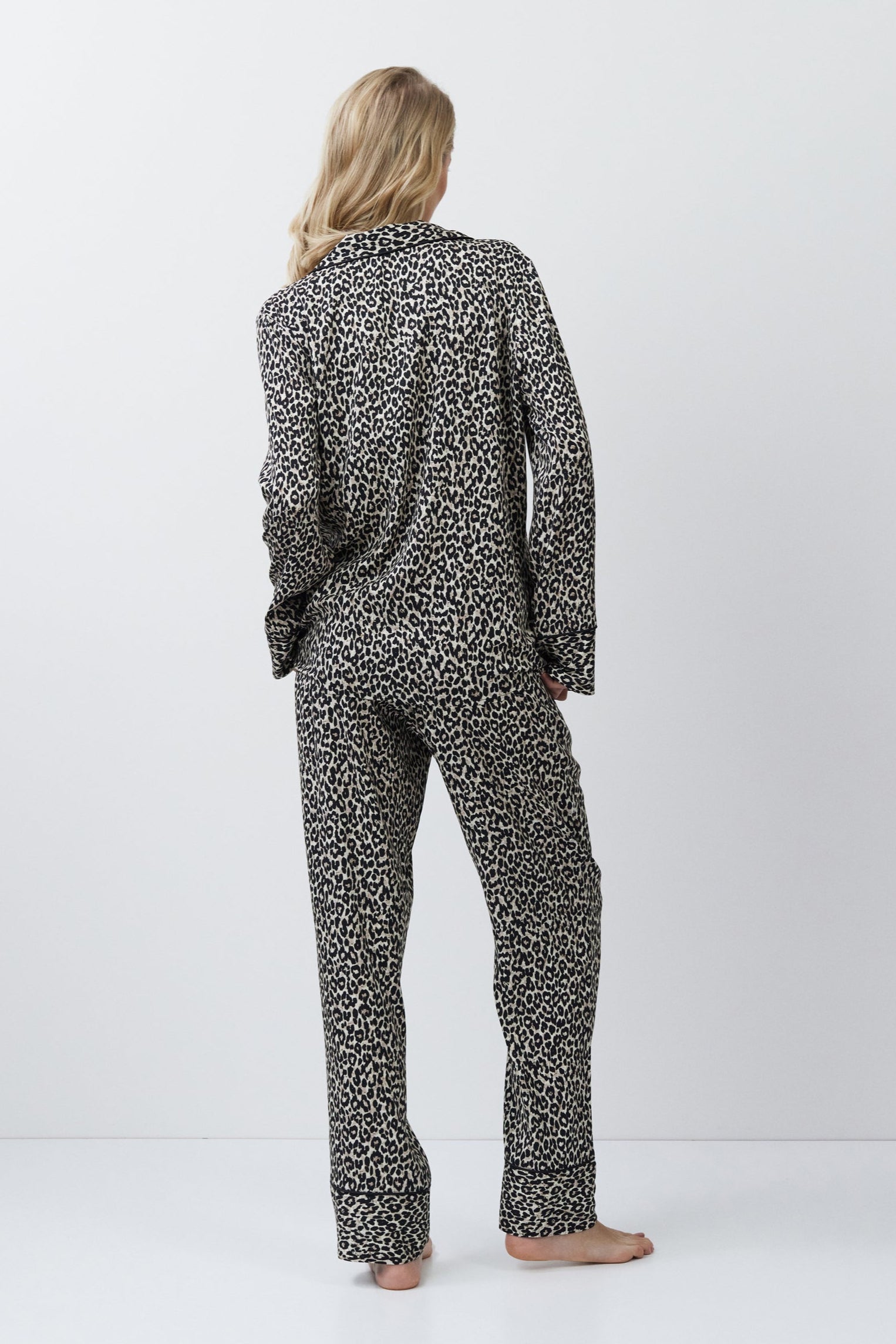 Person wearing a leopard patterned pajama set on a white background