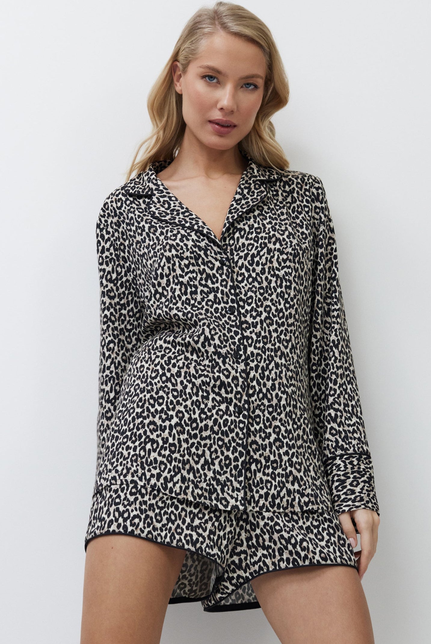 Woman wearing a leopard print pajama set with shorts against a white background