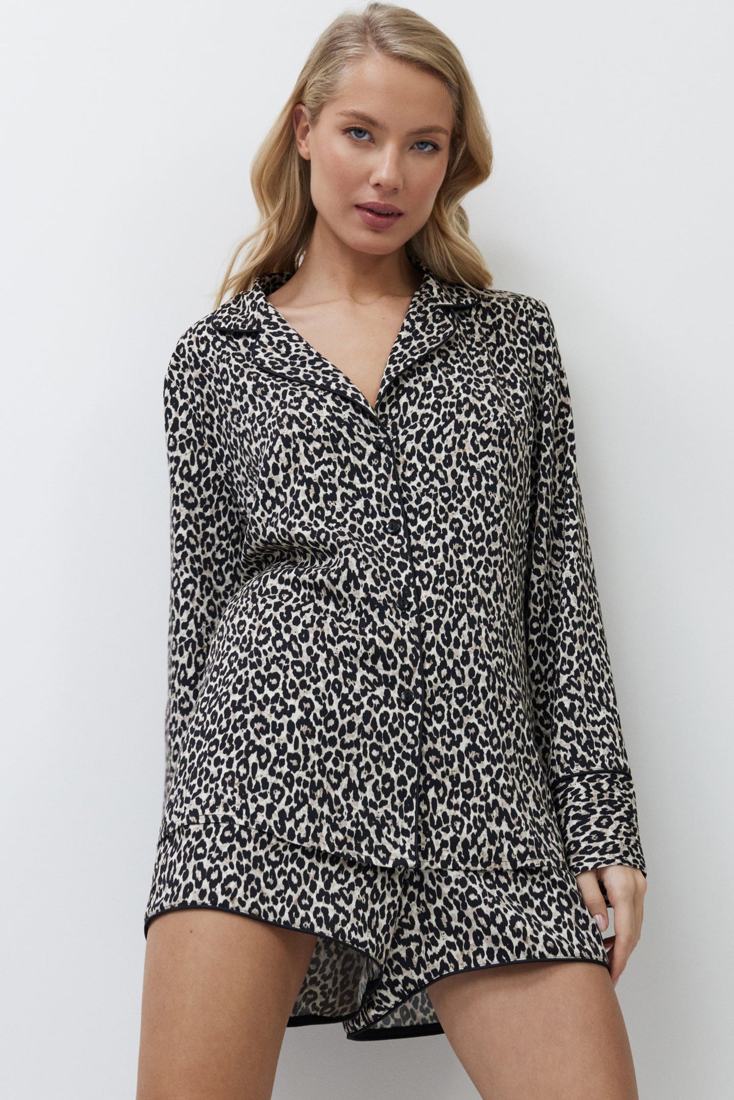 Woman wearing a leopard print pajama set with shorts against a white background