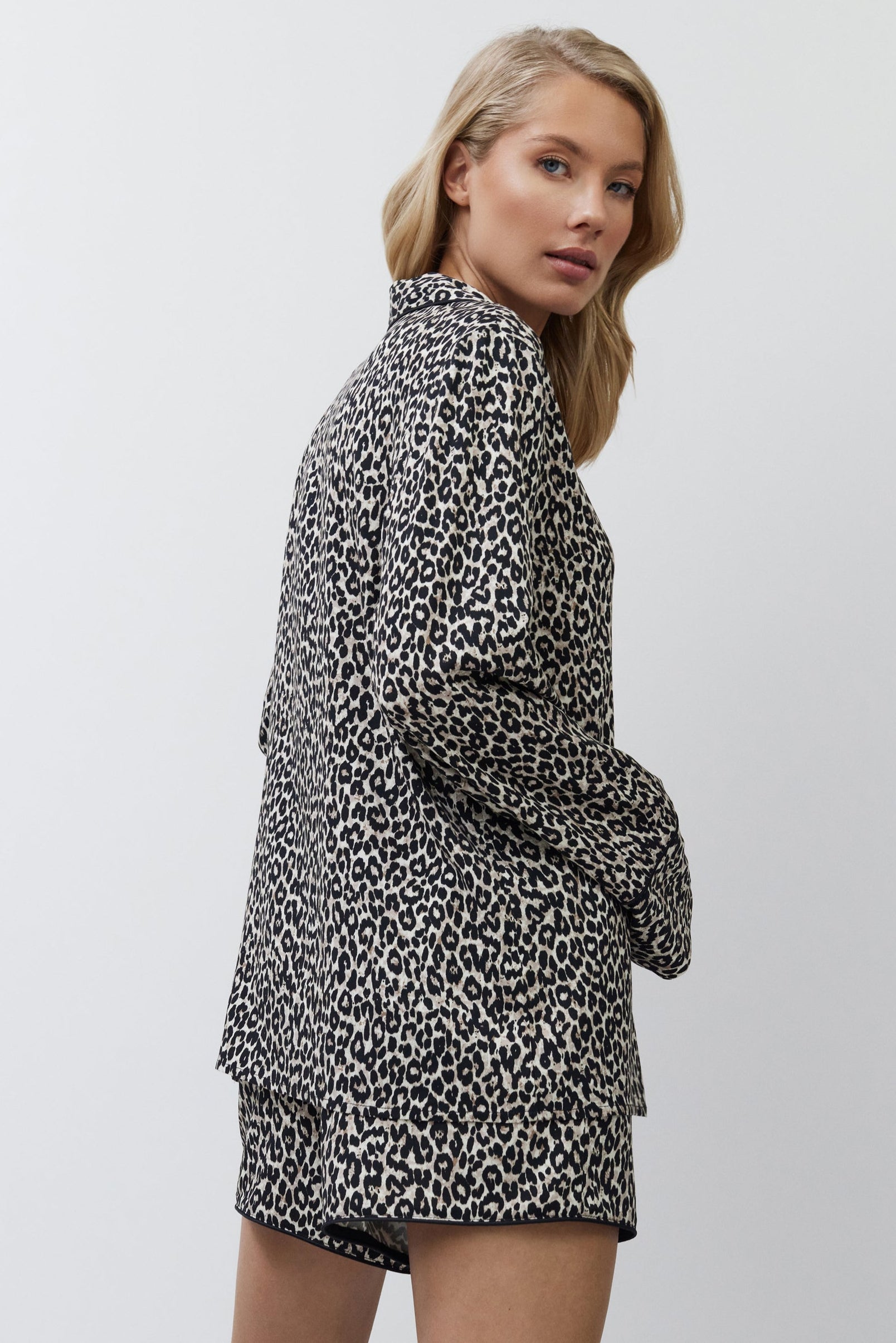 Woman wearing a leopard print outfit on a plain background